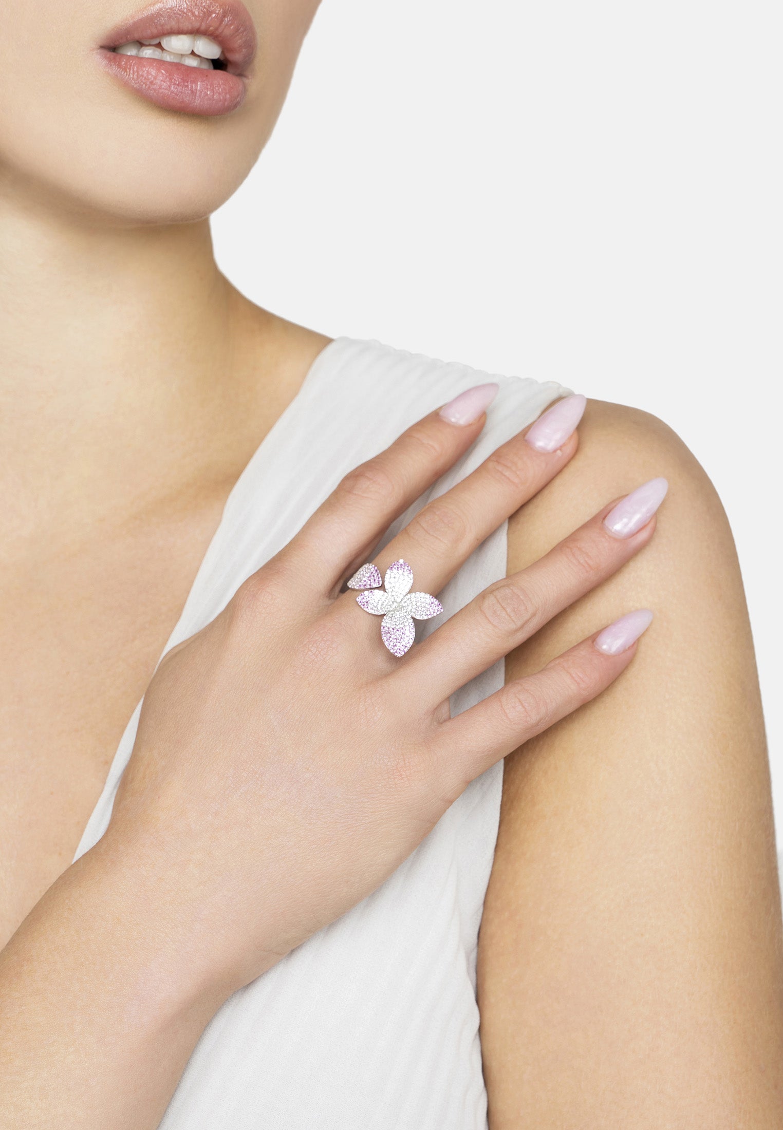 Close-up of a hand wearing a pink flower ring on a white background