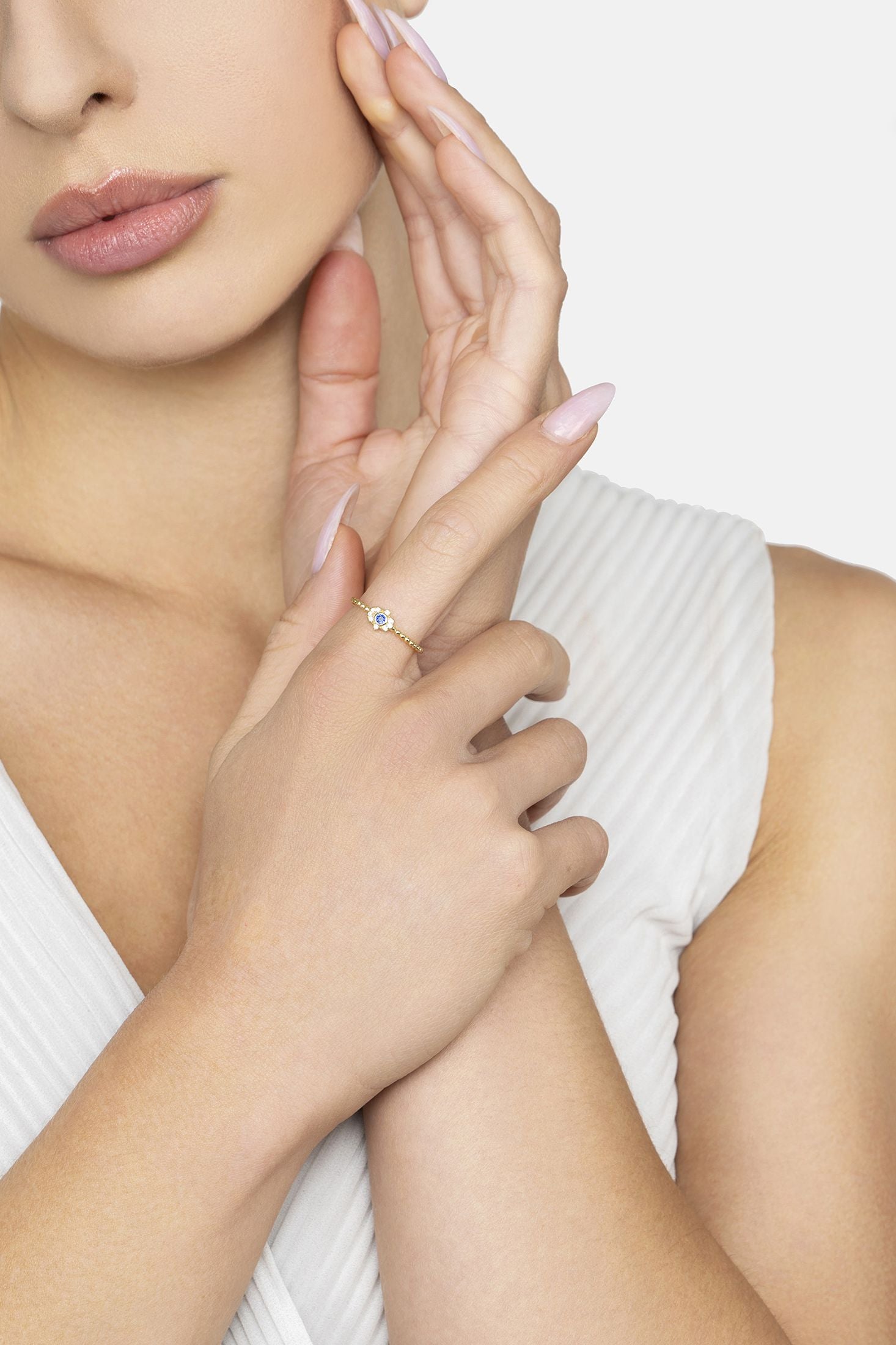 Close-up of a woman's hand wearing a diamond ring on a plain background