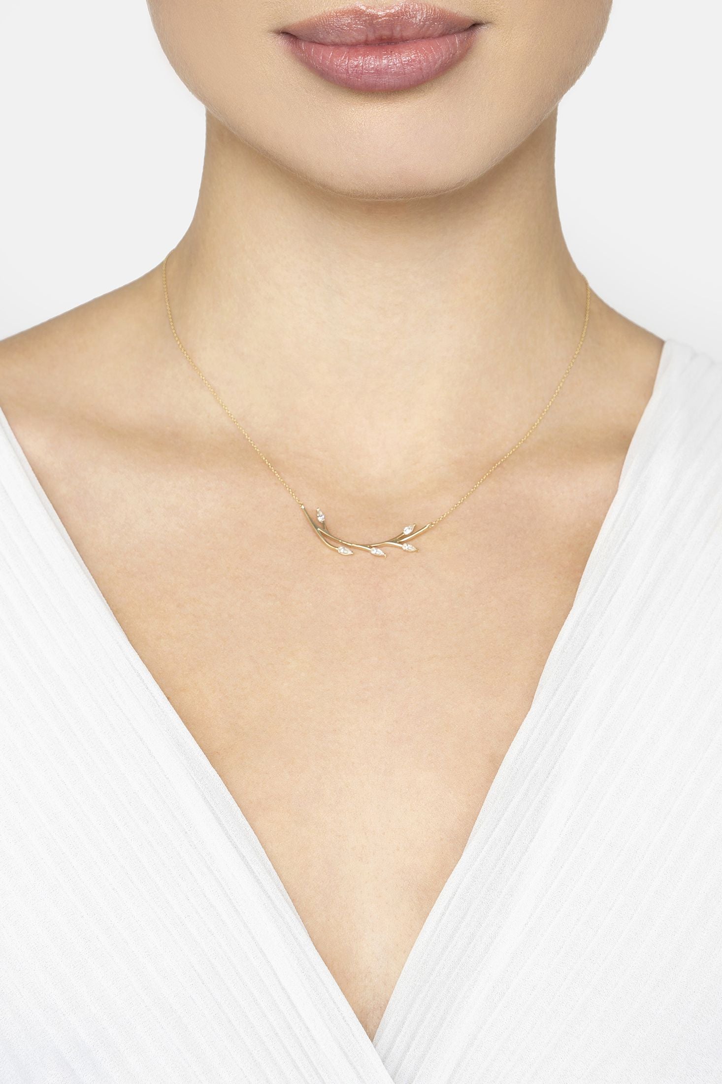 Gold necklace worn by a person on a white background