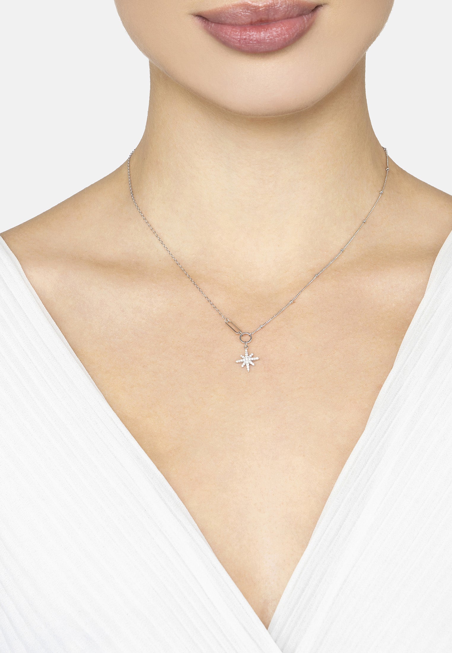 Necklace with a star-shaped pendant worn by a person against a neutral background