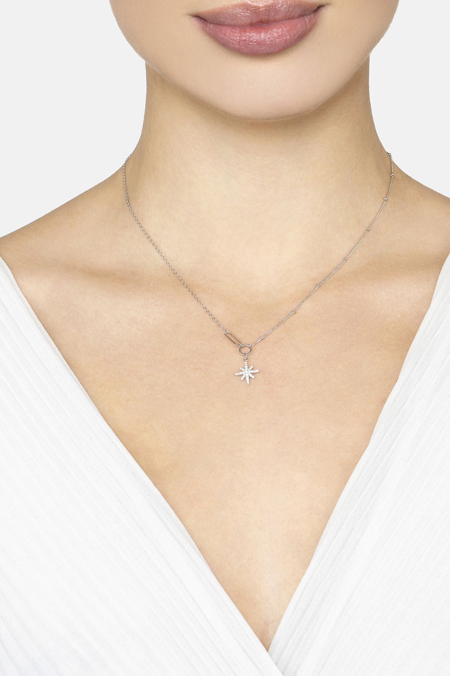 Necklace with a star-shaped pendant worn by a person against a neutral background