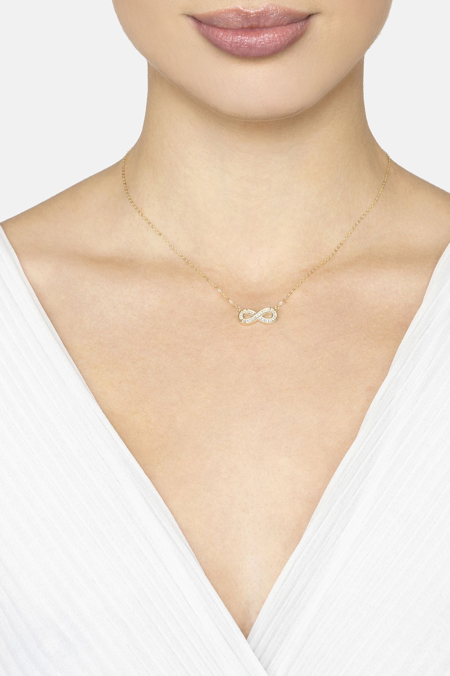 Necklace with an infinity symbol worn by a person against a white background