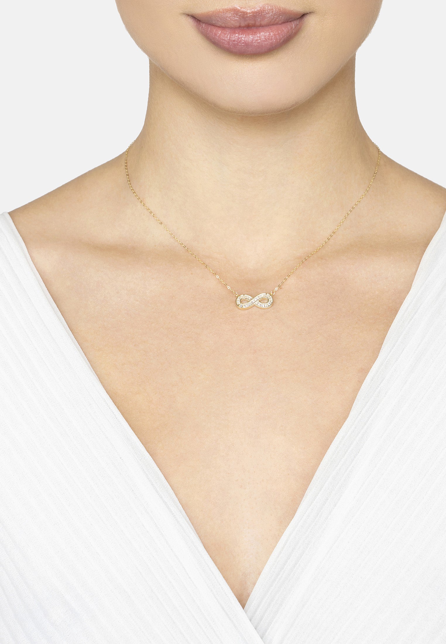 Necklace with an infinity symbol worn by a person against a white background