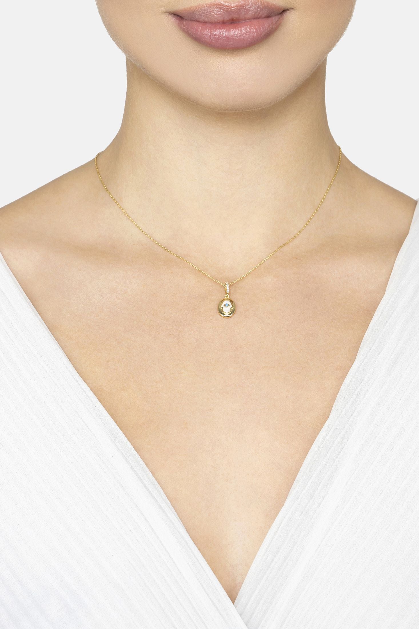 Gold necklace with a pendant worn by a model on a white background