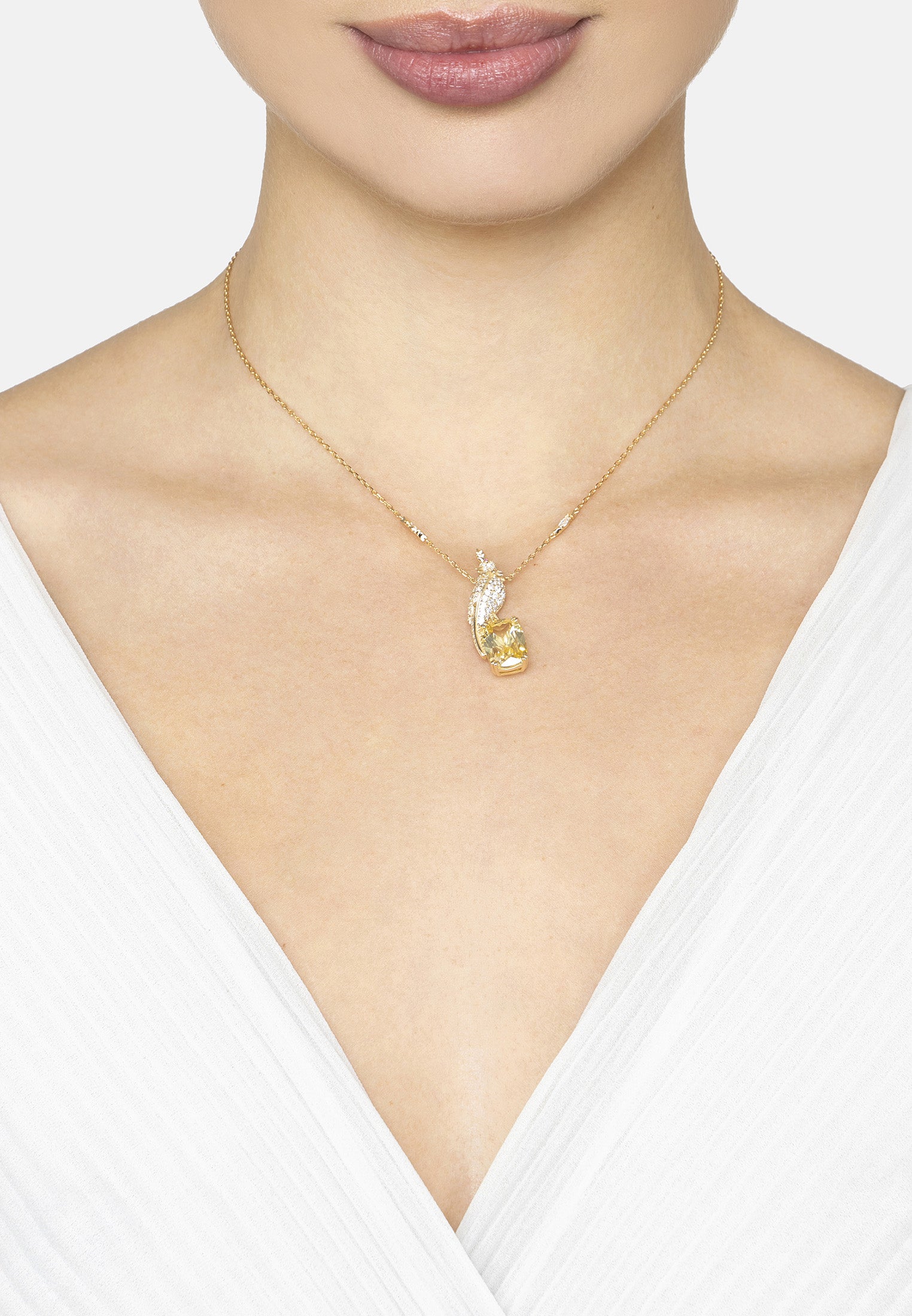 Gold necklace with a bird shaped pendant on a white background