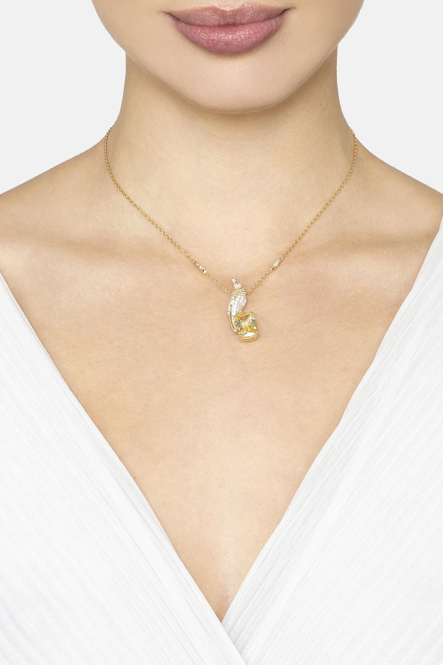 Gold necklace with a bird shaped pendant on a white background