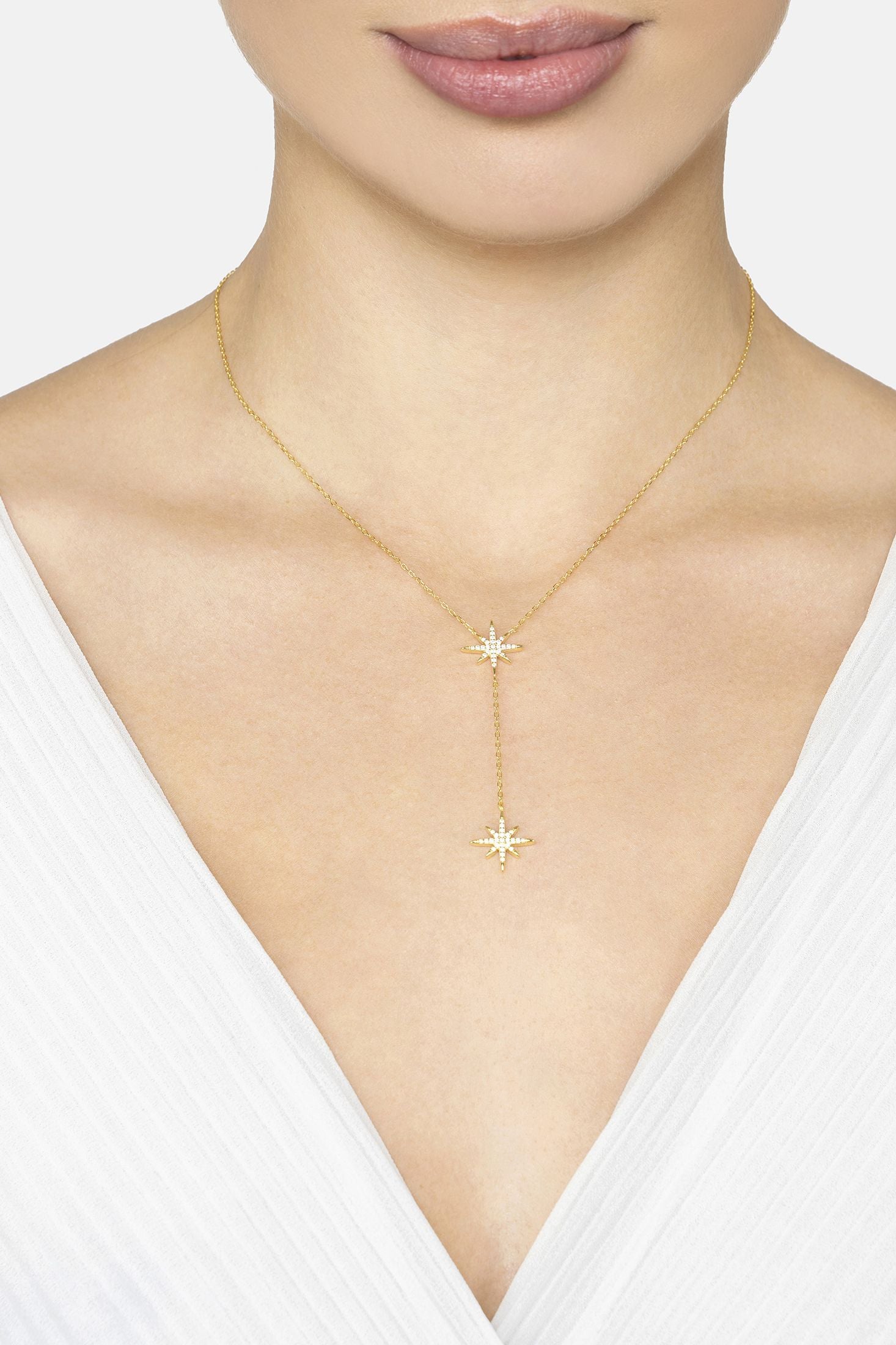 Gold necklace with star pendant on a model wearing a white top