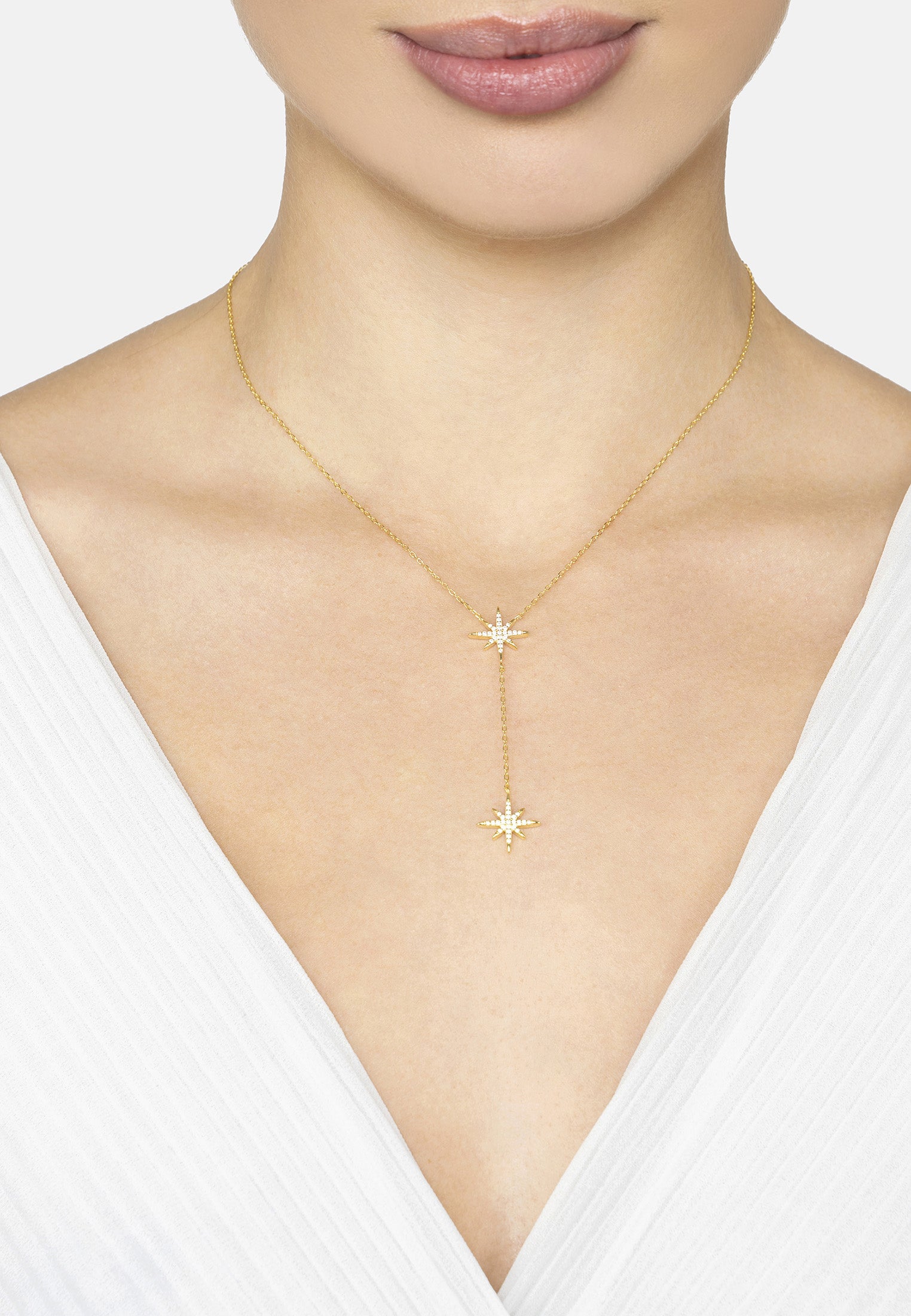 Gold necklace with star pendant on a model wearing a white top