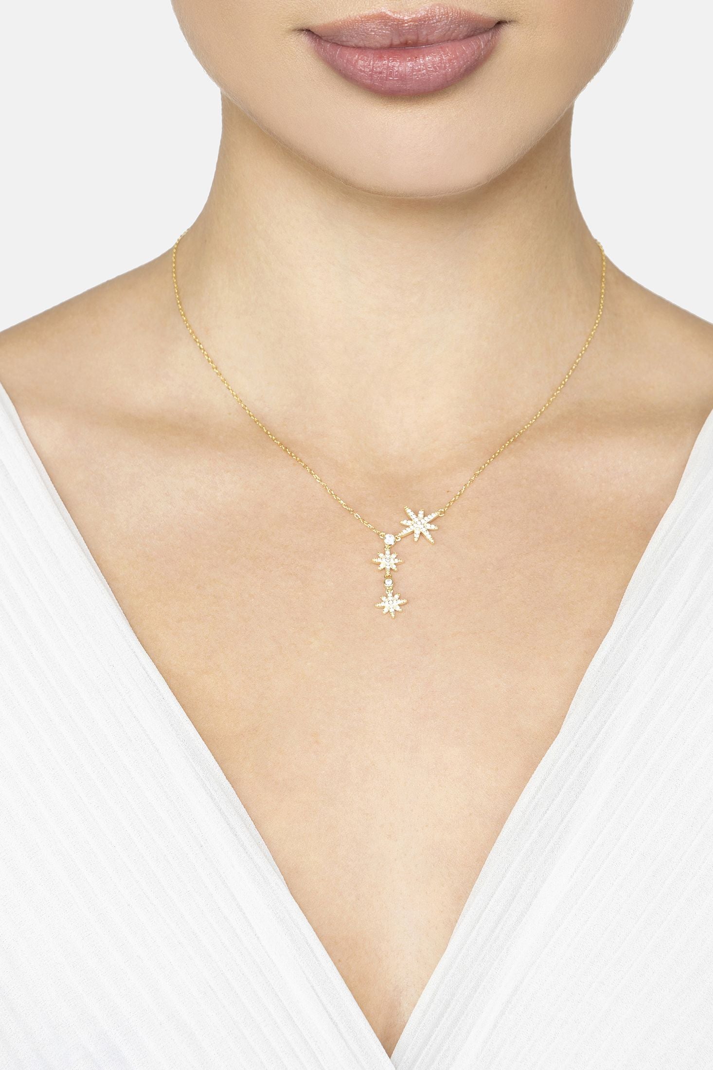 Gold necklace with star-shaped pendant worn by a model against a white background