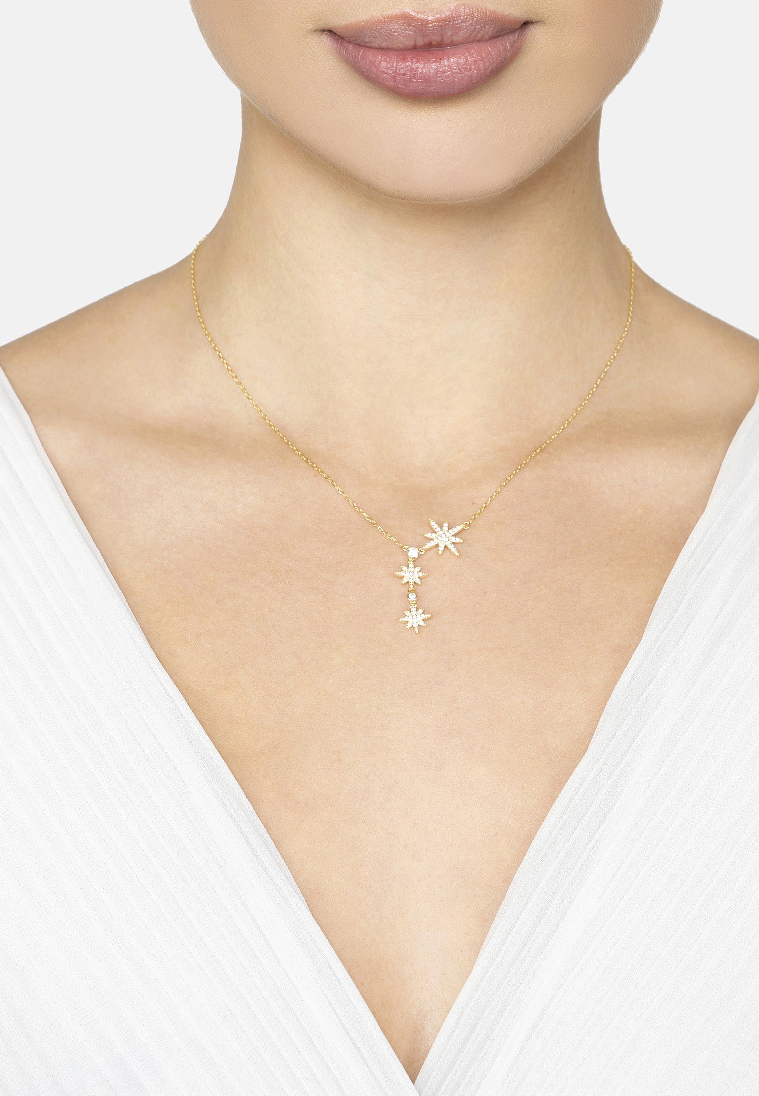 Gold necklace with star-shaped pendant worn by a model against a white background
