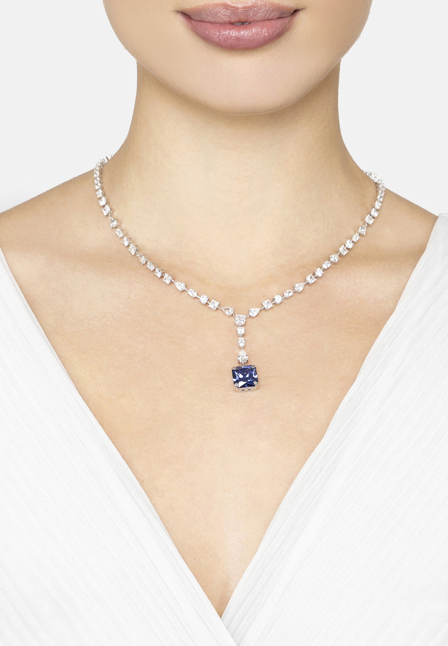 Diamond necklace with a central blue gemstone worn by a model on a white background