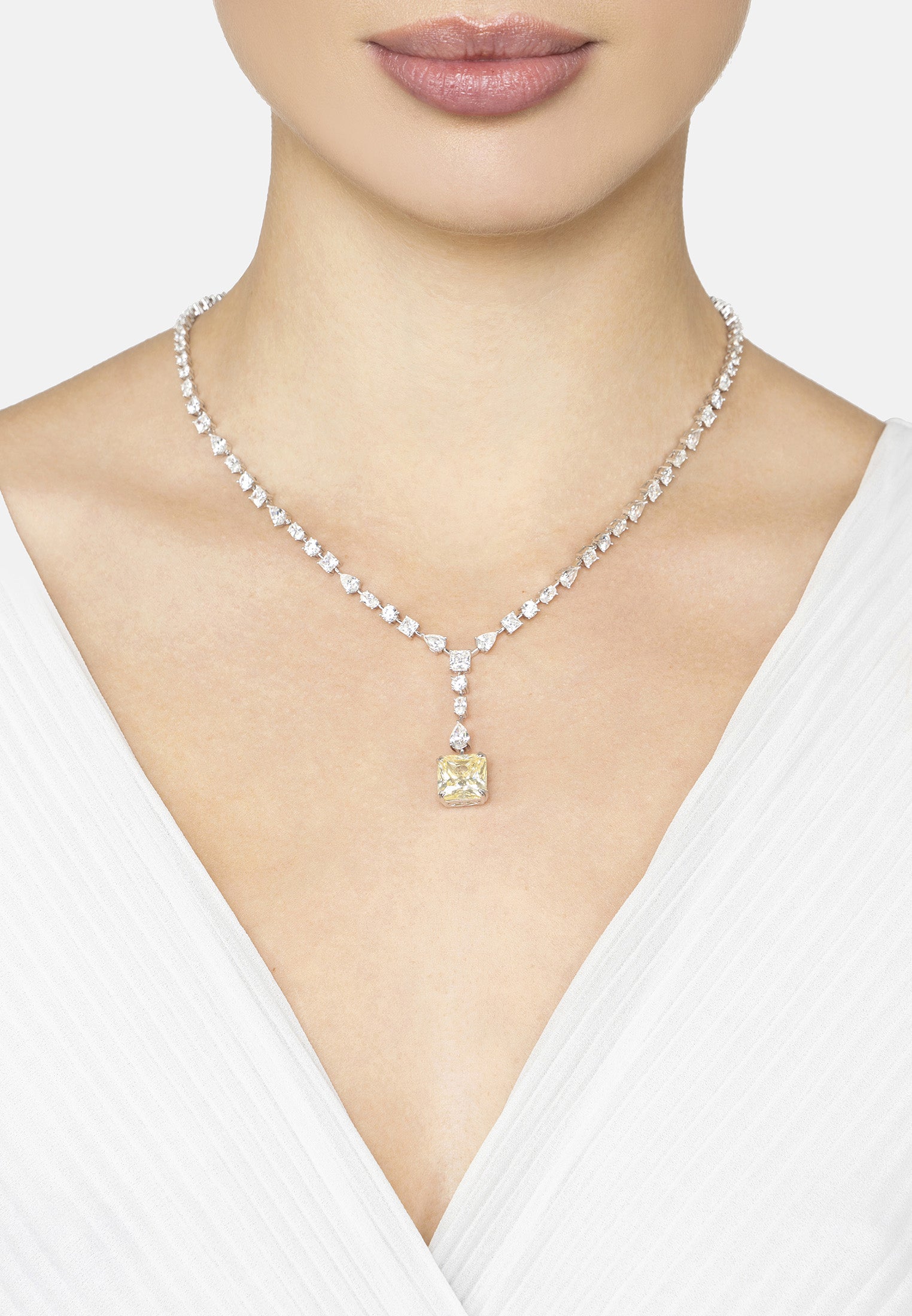 Necklace with a yellow pendant worn by a person against a white background