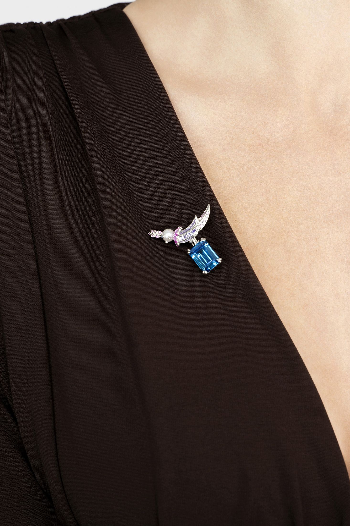 Blue gemstone brooch on a black dress with a white background