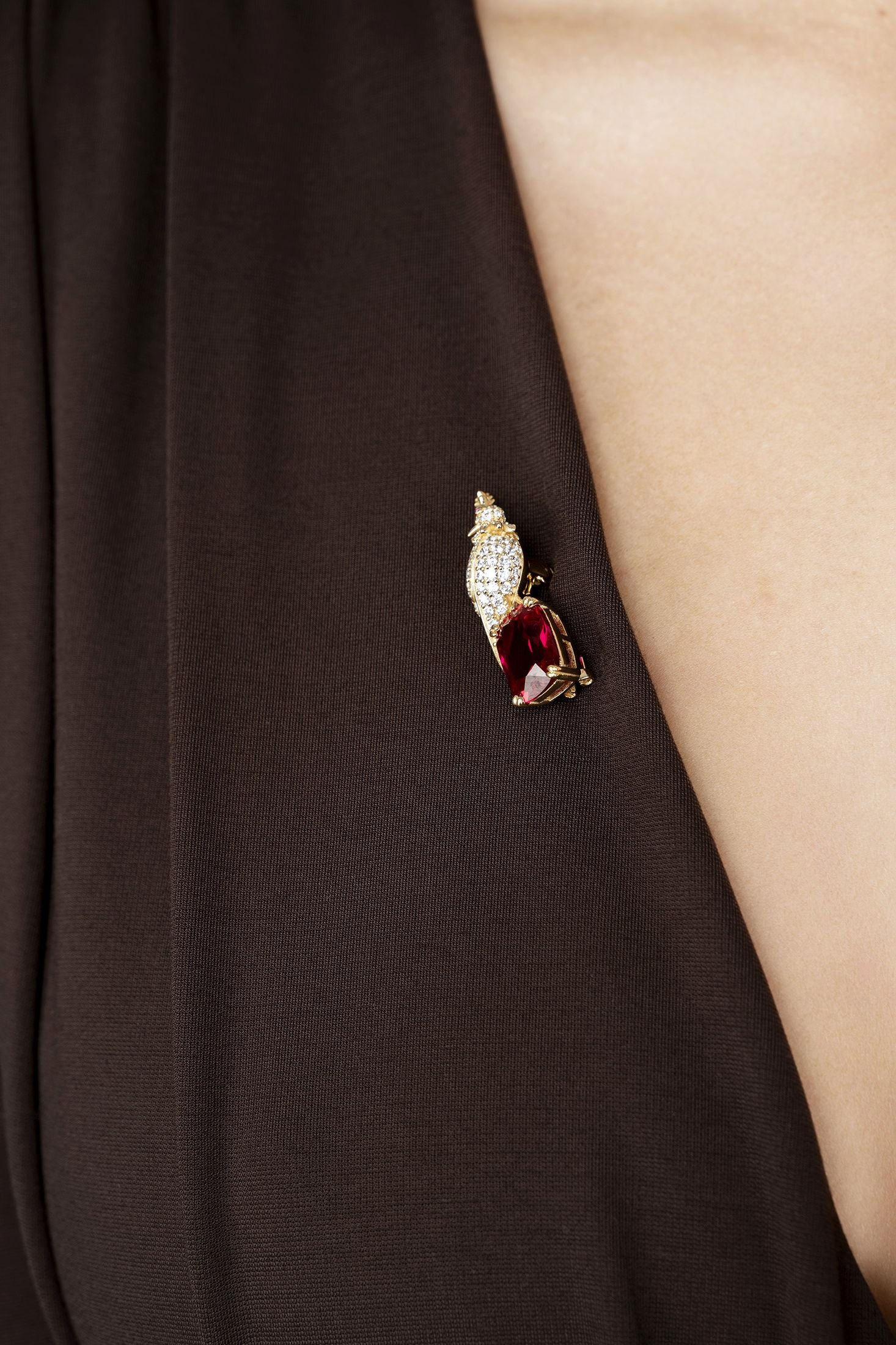 Close-up of a decorative gold brooch on a dark fabric background