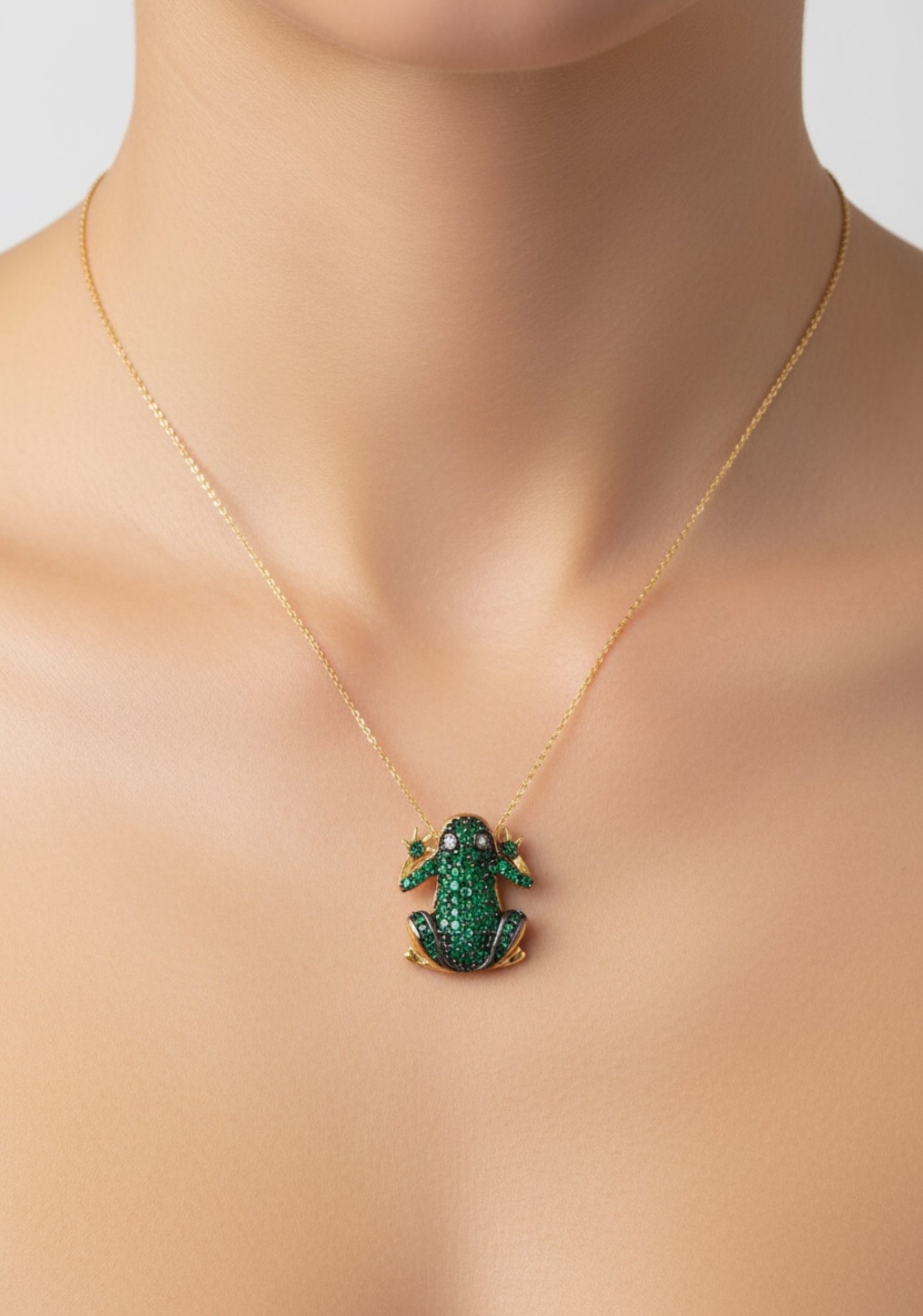 Gold necklace with a green frog pendant on a woman