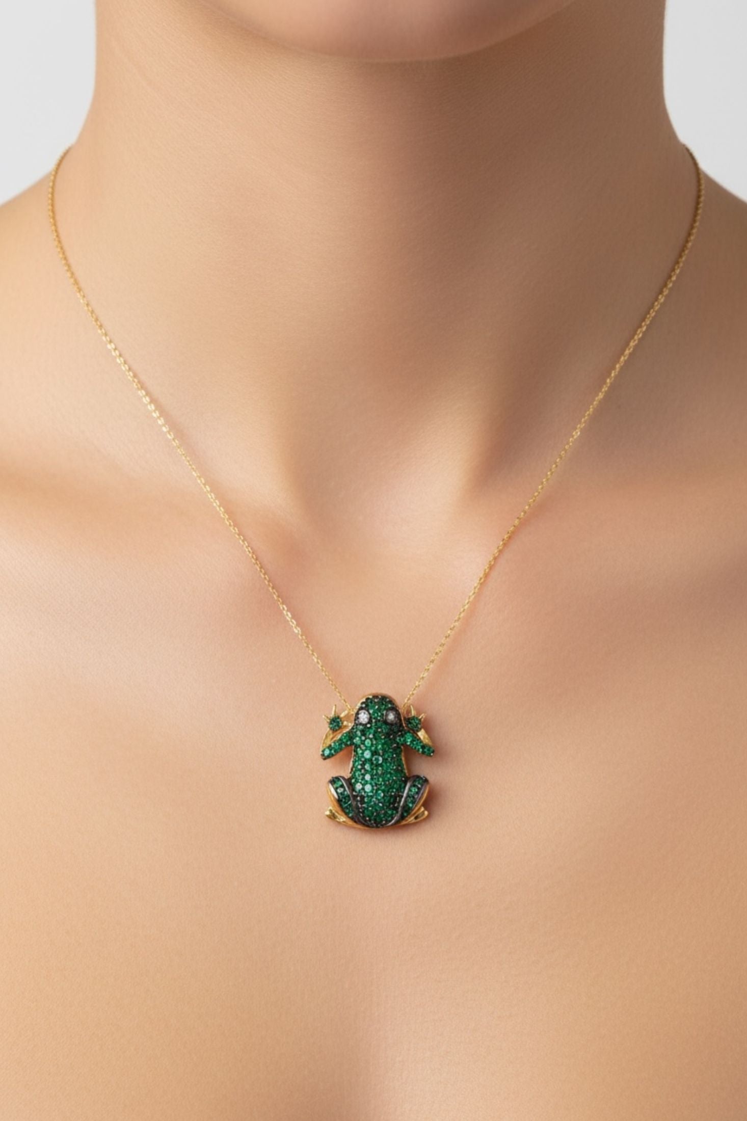 Gold necklace with a green frog pendant on a woman