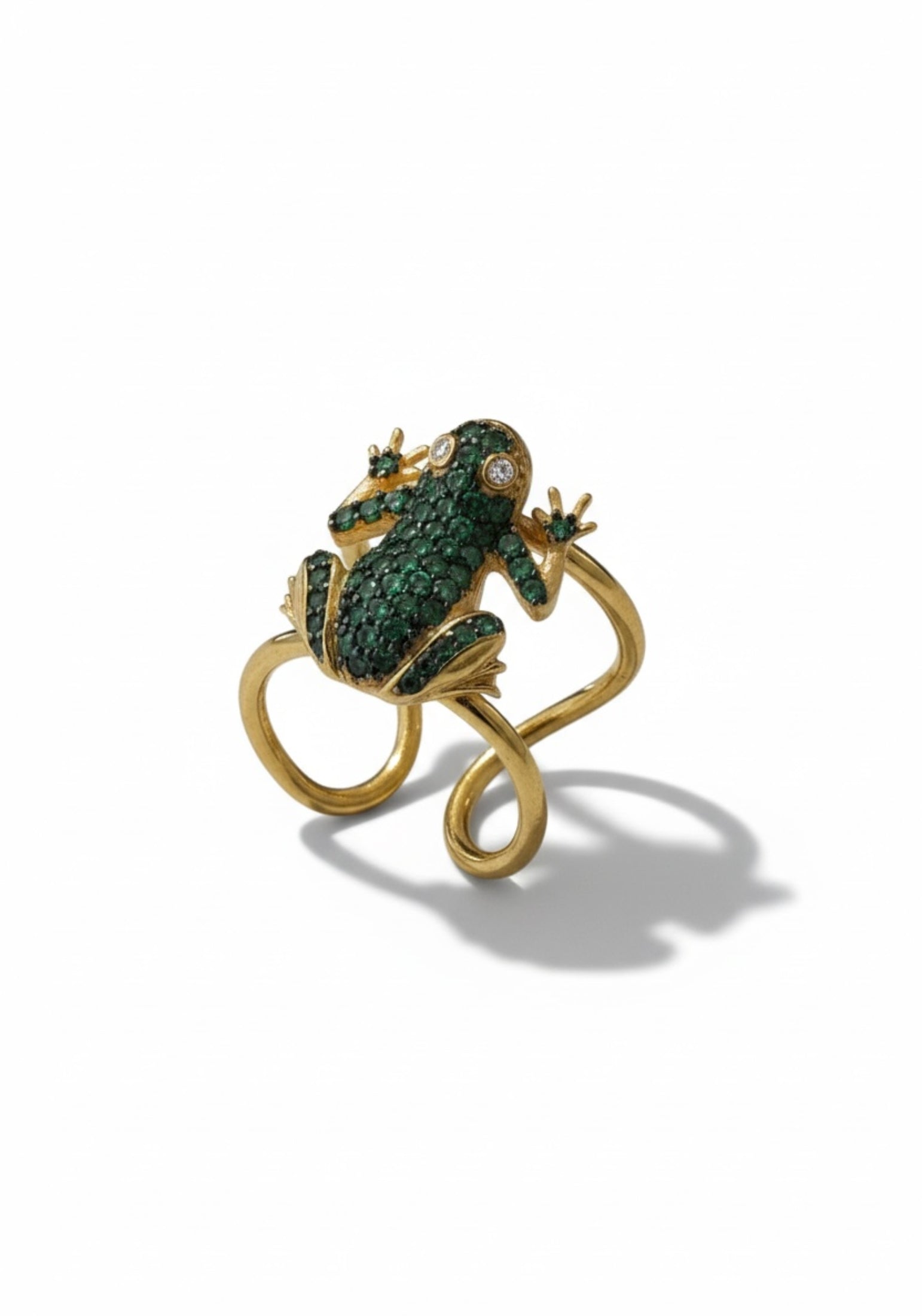 Gold frog-shaped ring with green gemstones on a white background
