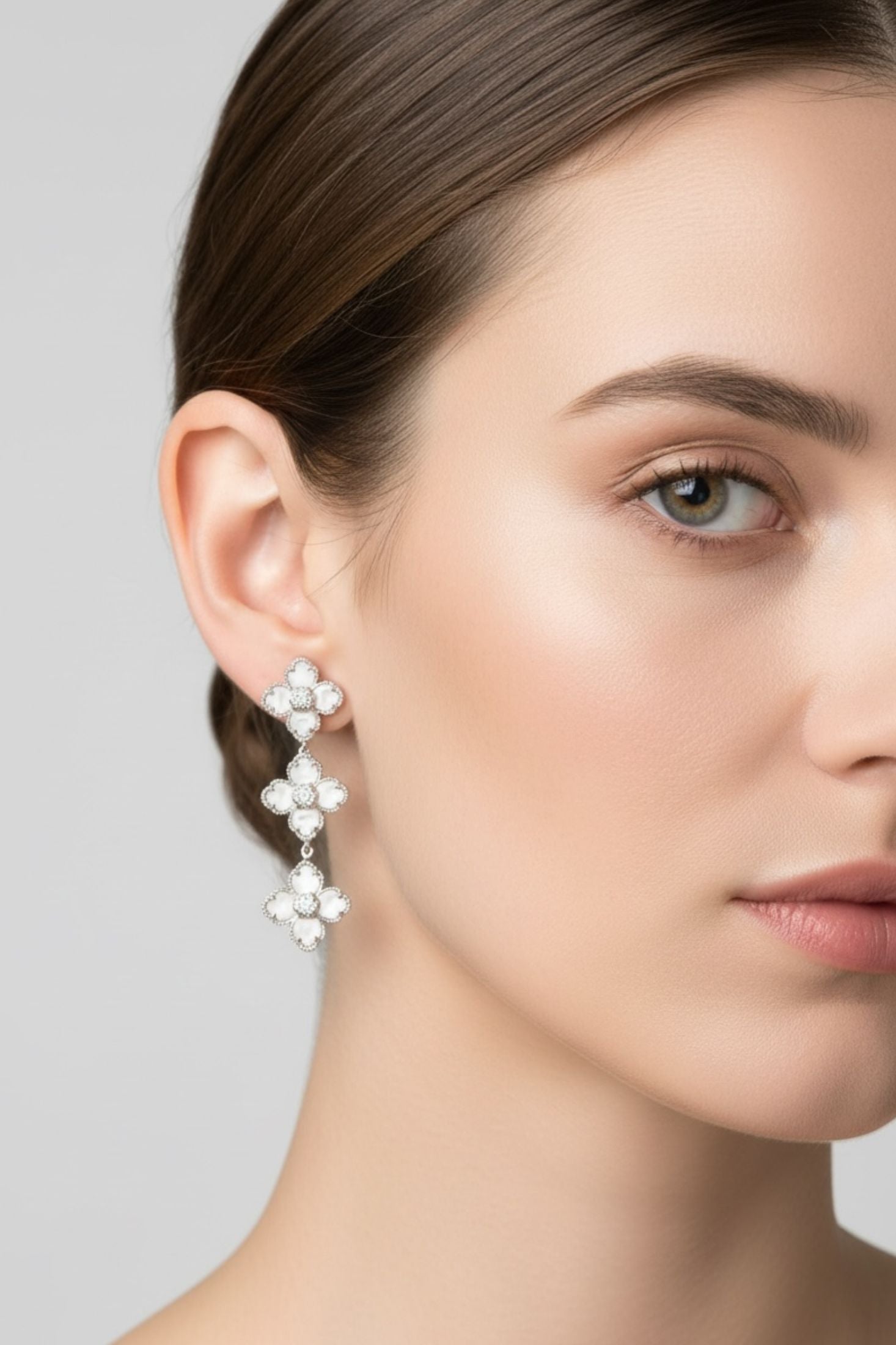 Close-up of a woman wearing floral earrings against a neutral background