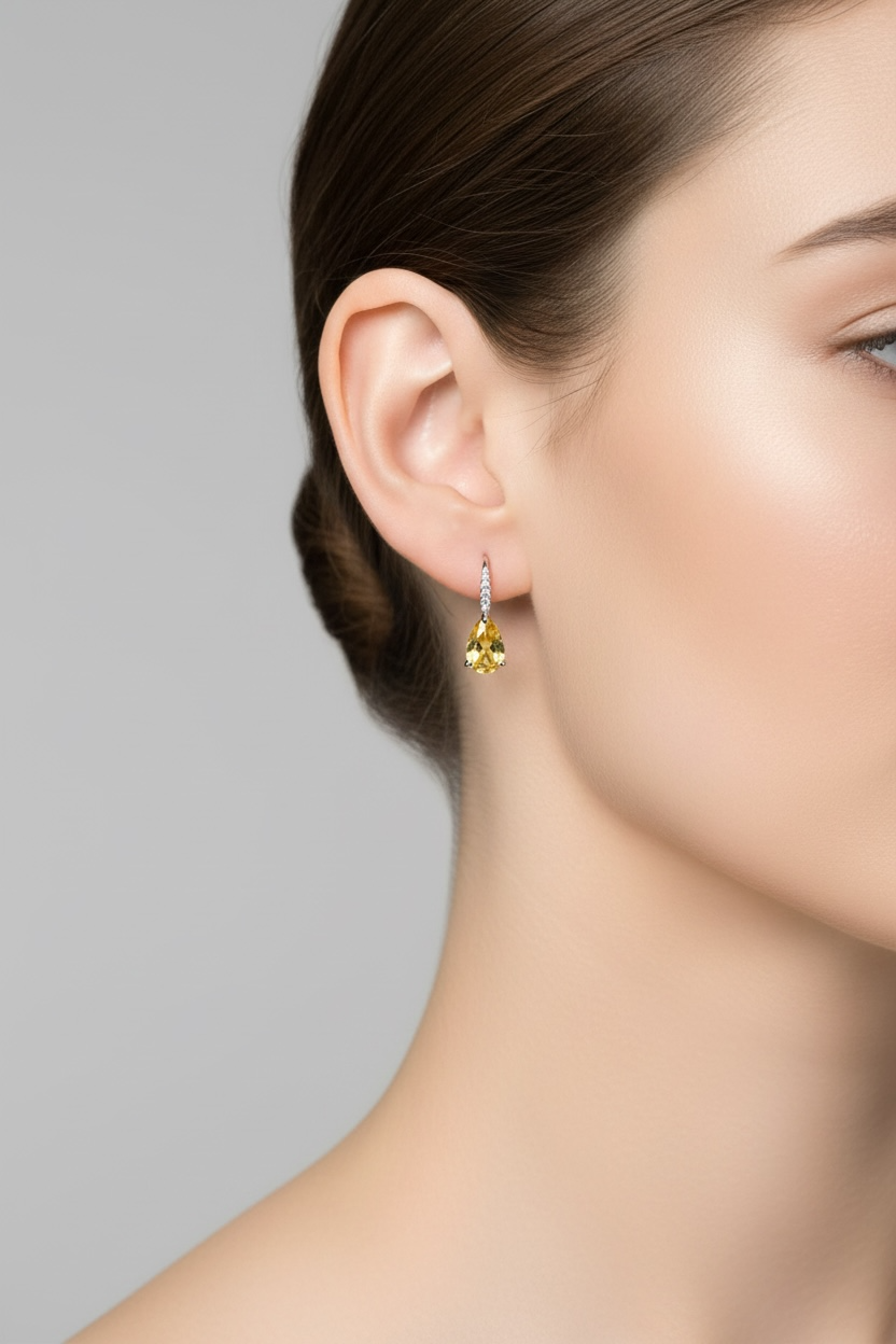 Close-up of a woman wearing a yellow gemstone earring on a gray background