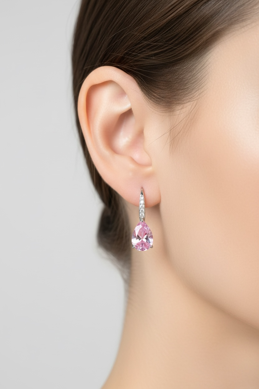 Pink teardrop earring worn by a model on a neutral background