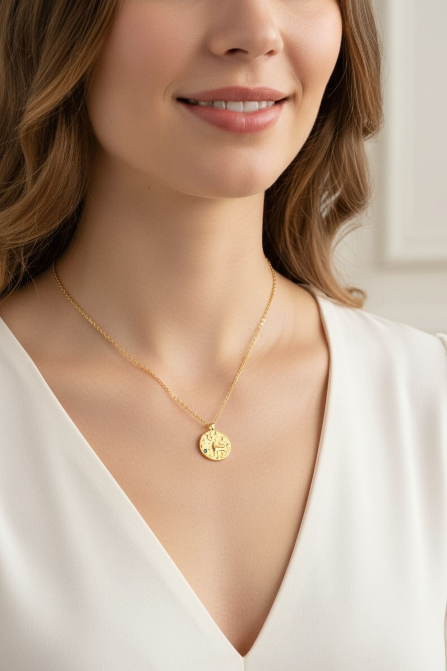 Woman wearing a gold necklace with a round pendant against a neutral background