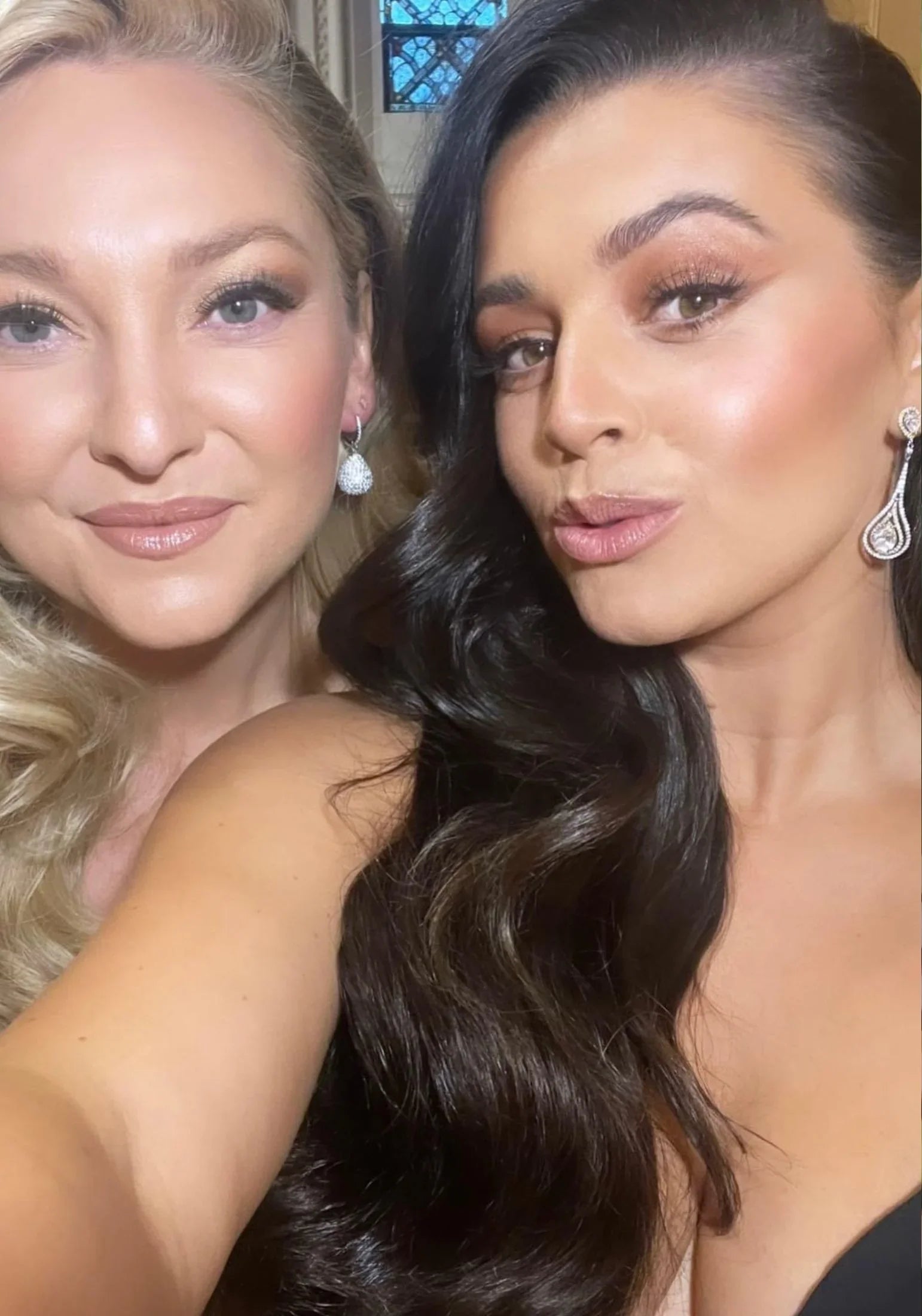 Two women with diamond earrings posing for a selfie.