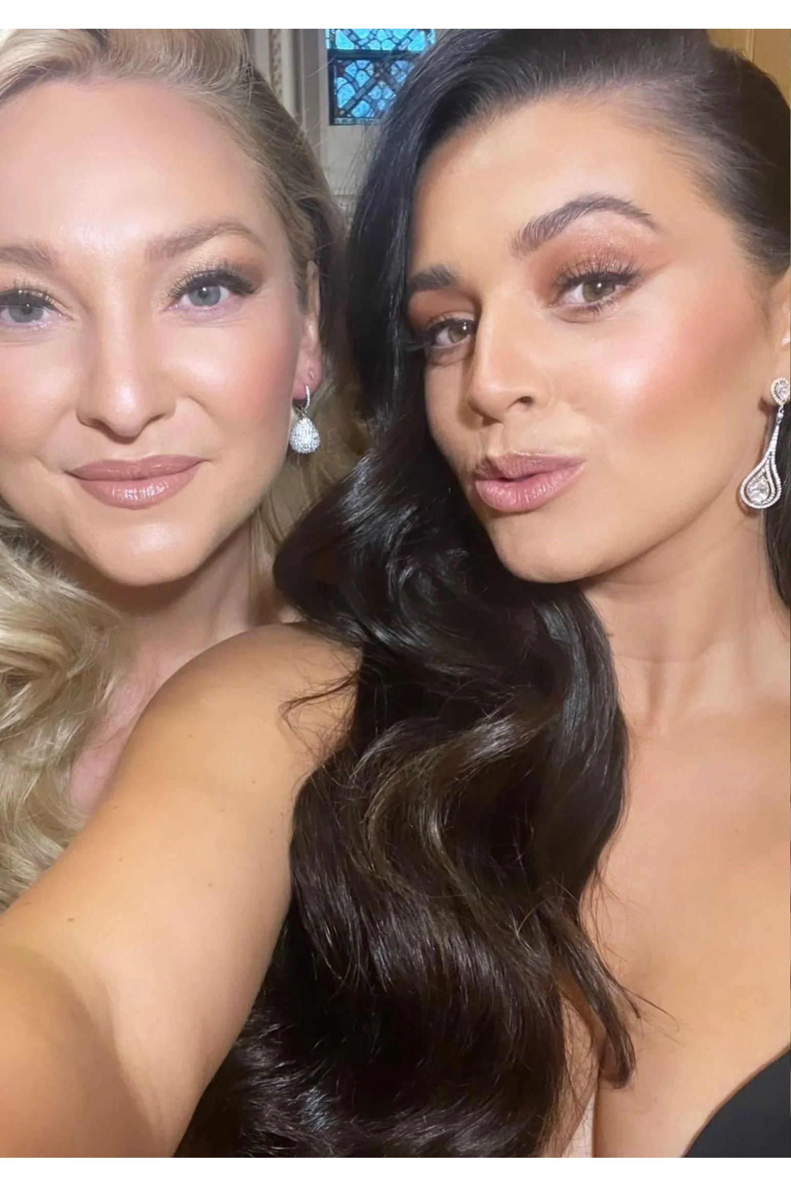 Two women with diamond earrings posing for a selfie.