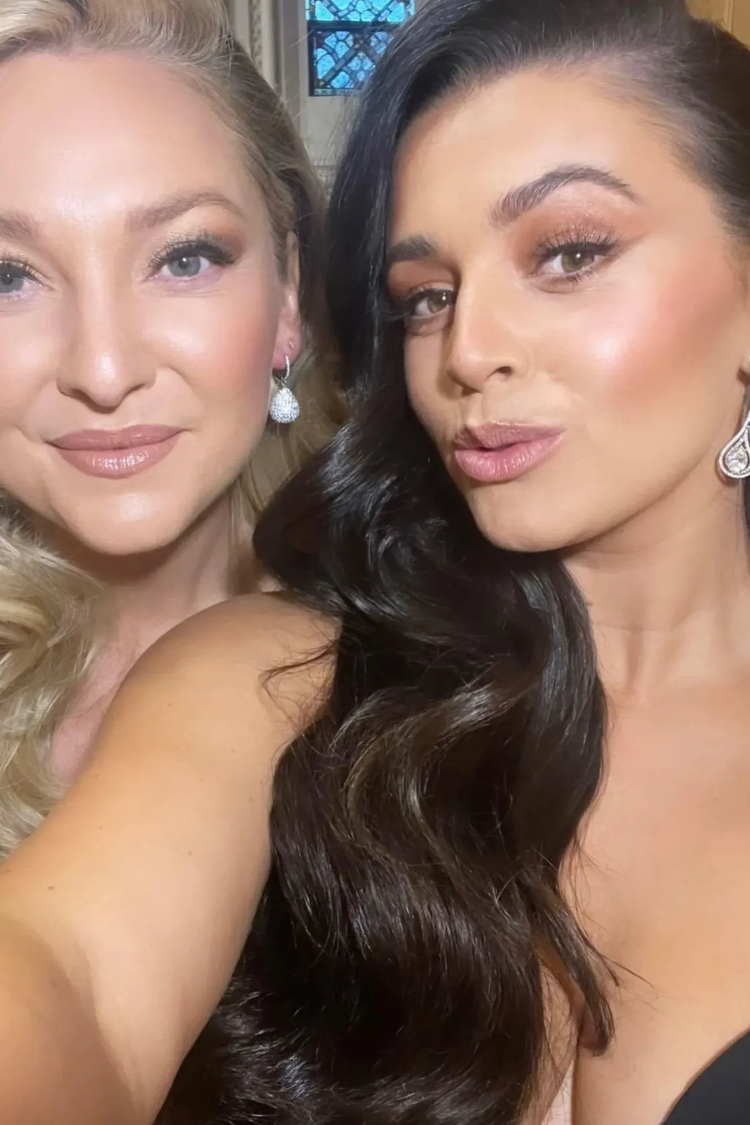 Two women with diamond earrings posing for a selfie.