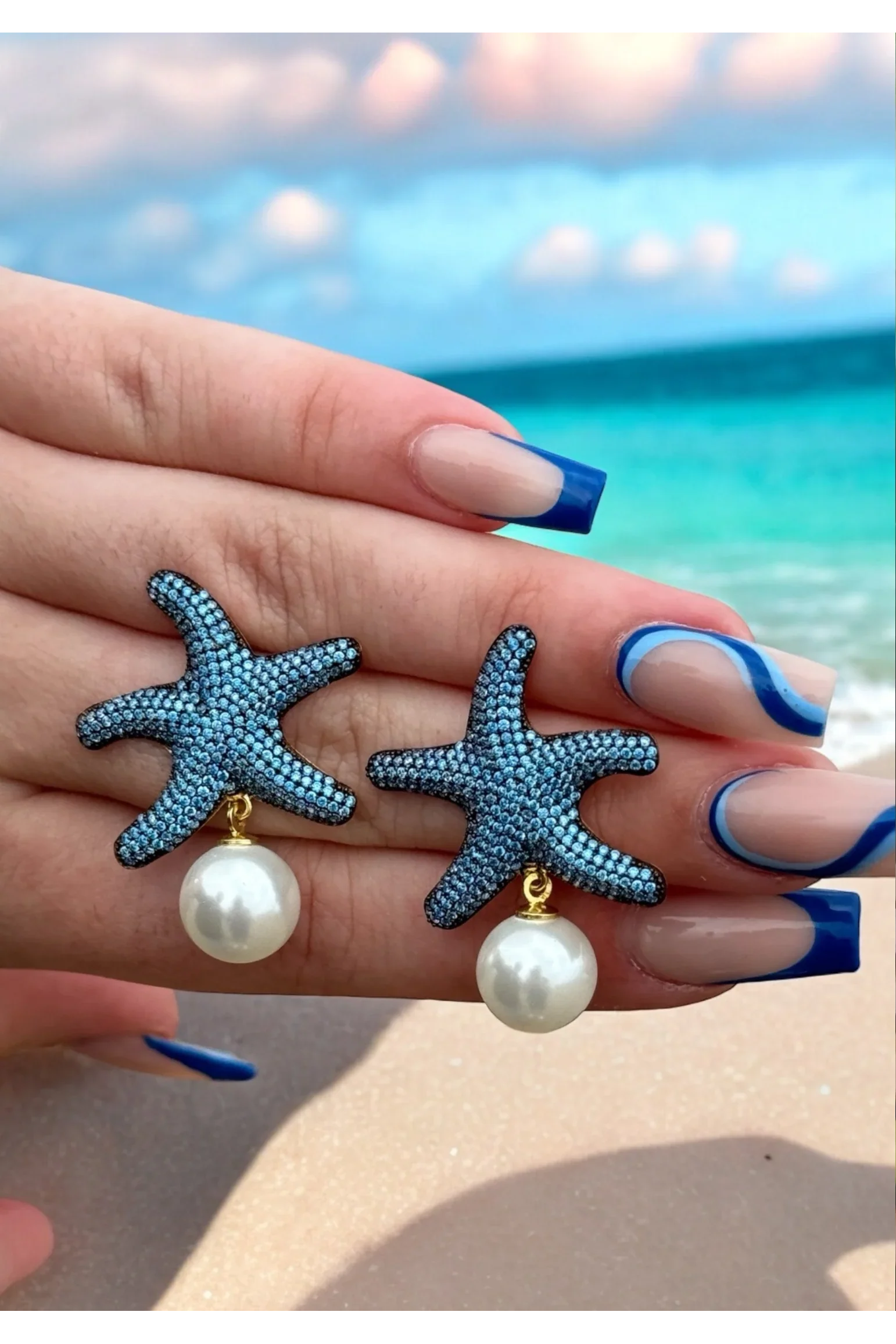 The earrings held up by a hand model.