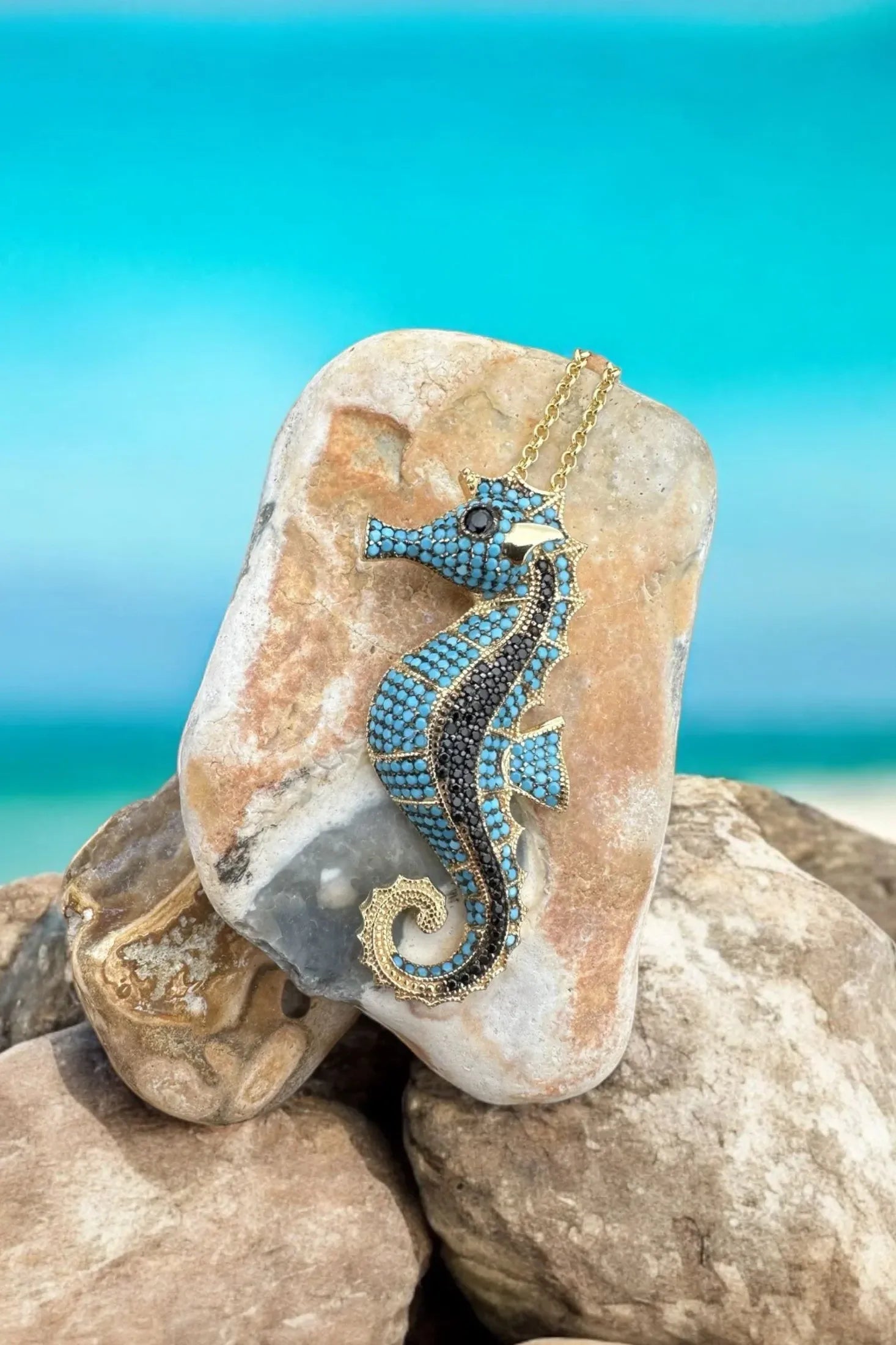 The necklace against rocks on a beach.