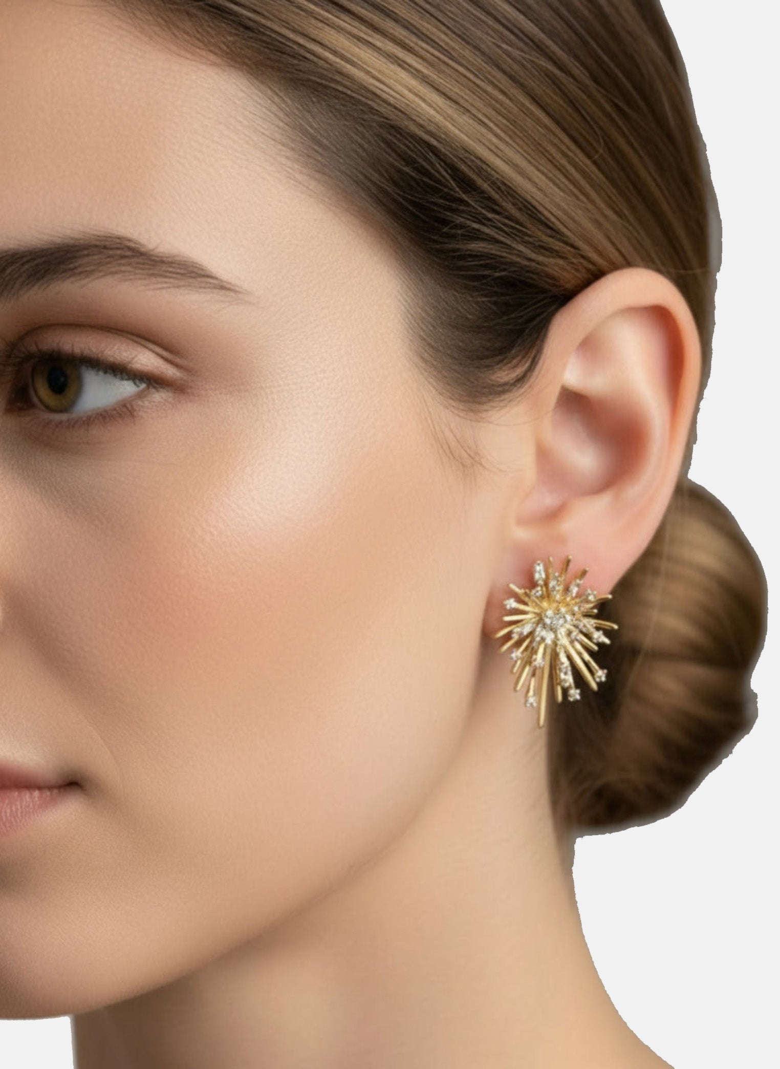 Close-up of a woman wearing a gold earring with a starburst design.