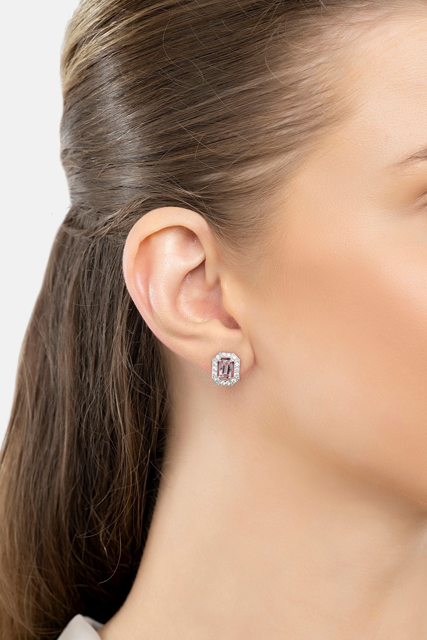 Close-up of a person wearing a pink gemstone earring with a blurred background