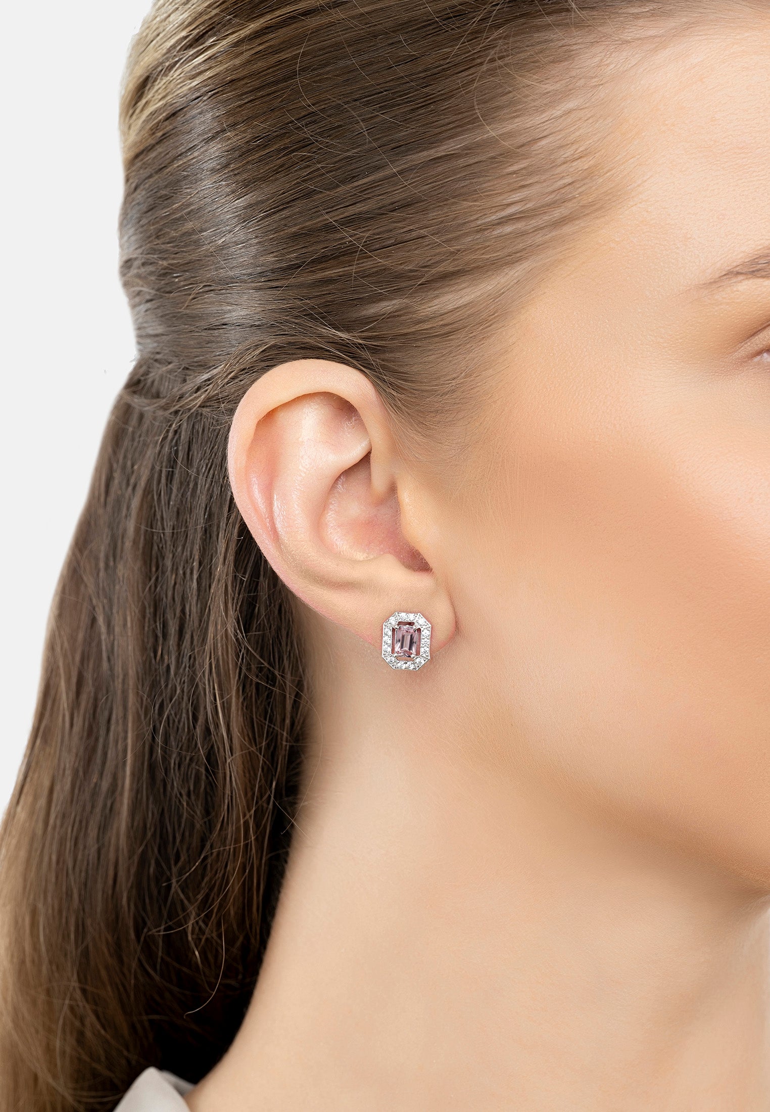 Close-up of a person wearing a pink gemstone earring with a blurred background