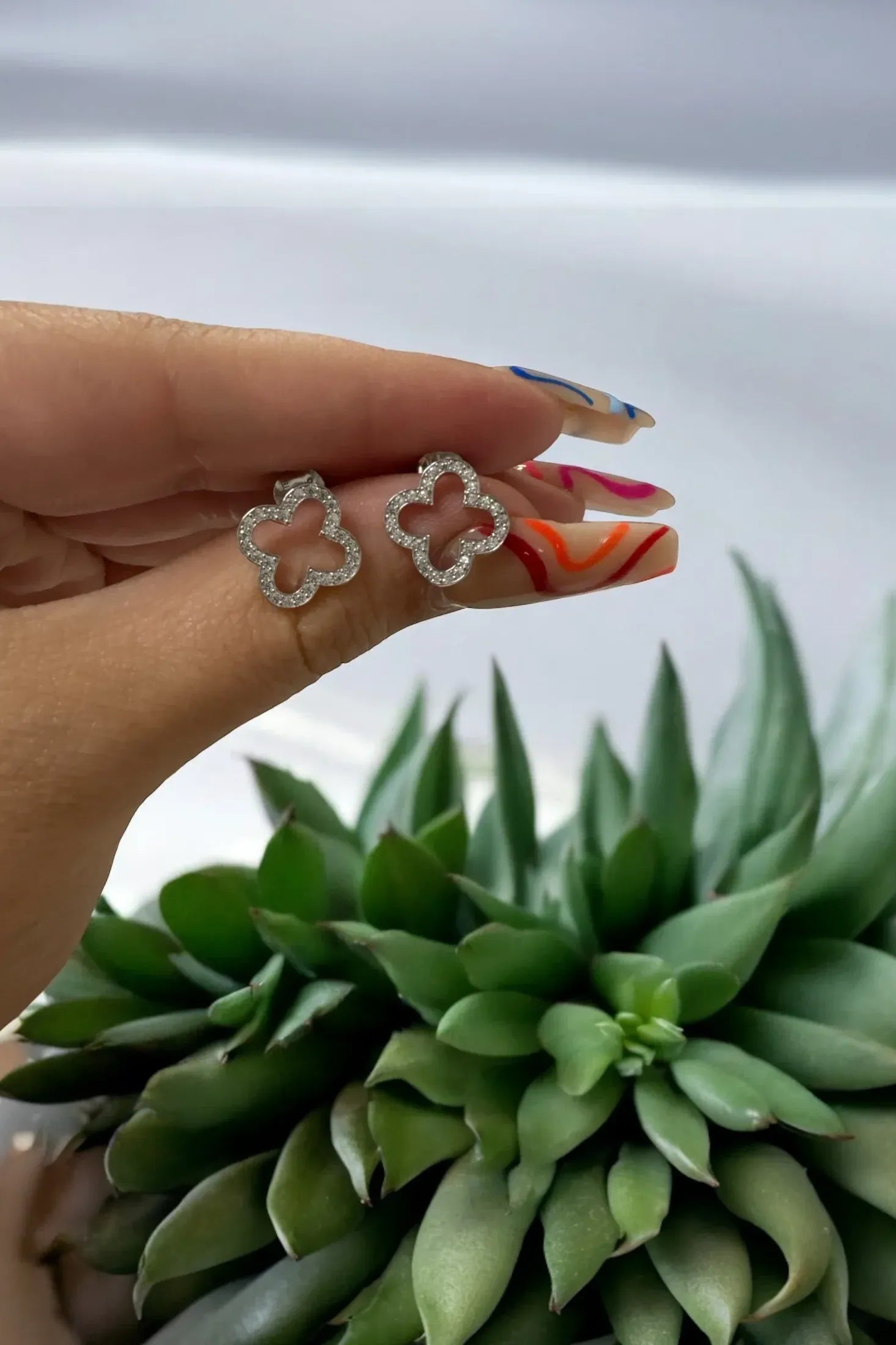 The earrings held up by a hand model.