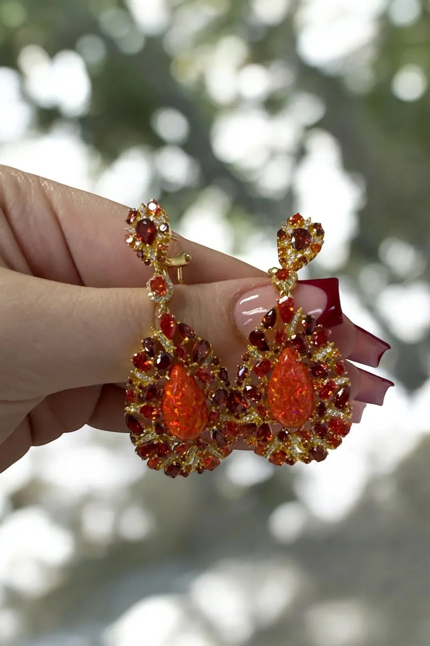 The earrings held up by a hand model.