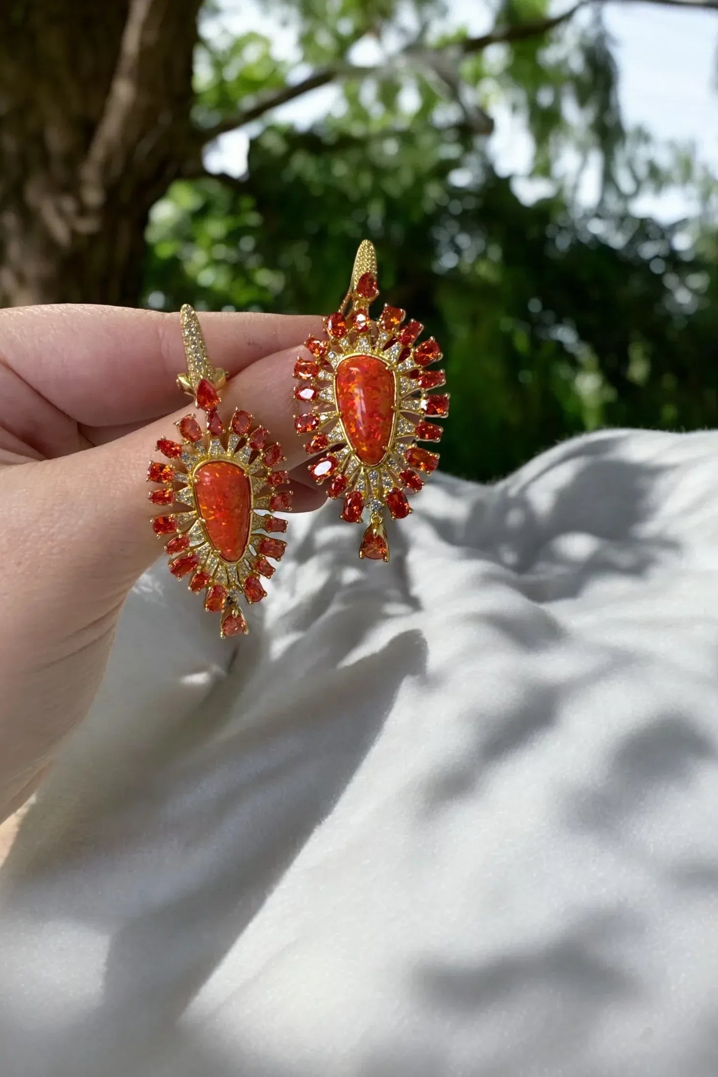 The earrings held up by a hand model.