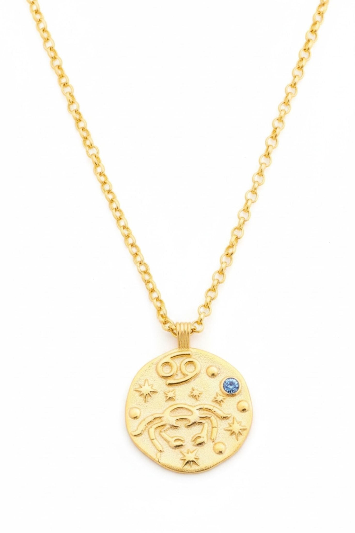 Gold necklace with a round pendant featuring astrological symbols on a white background