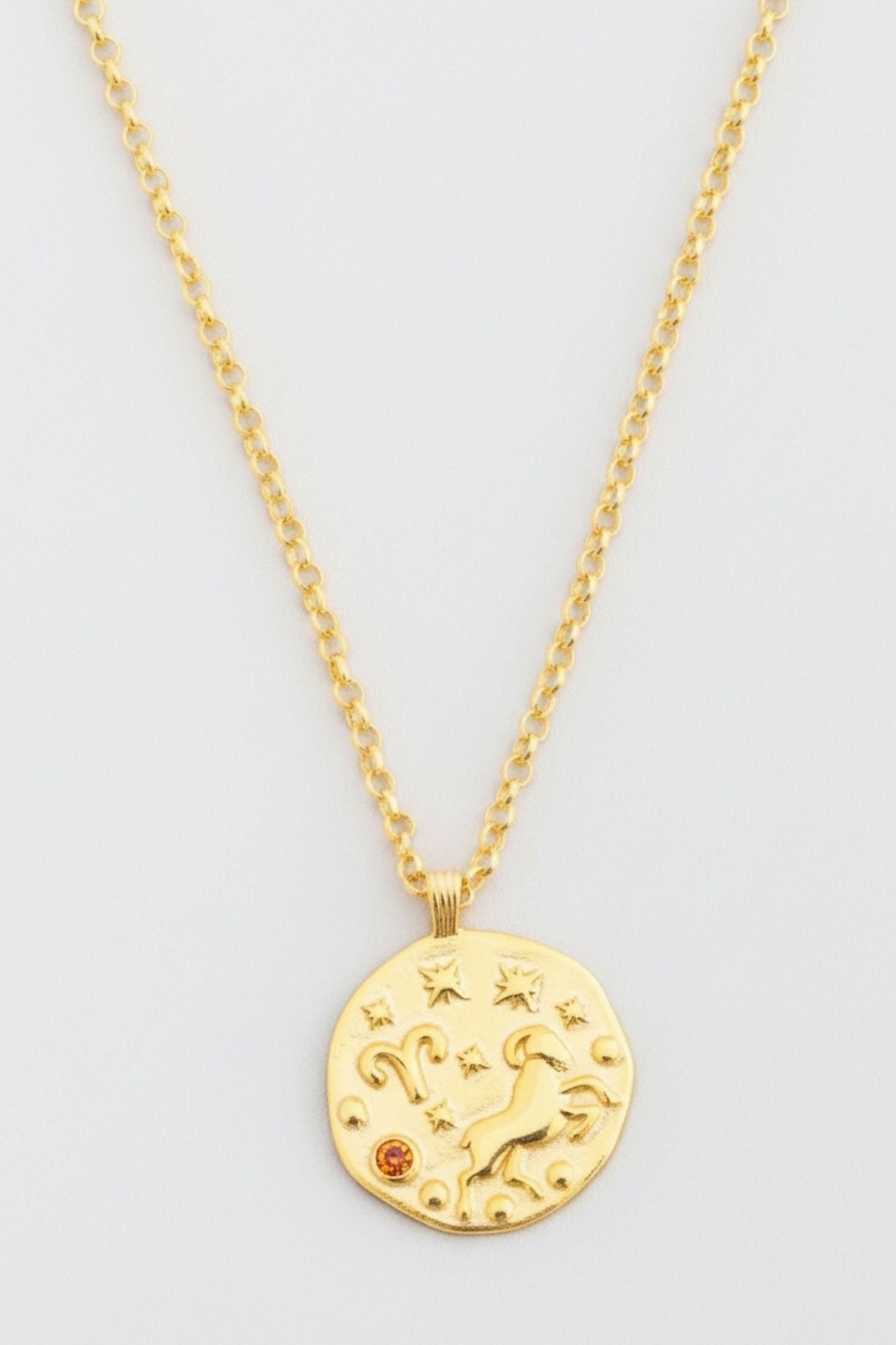 Gold necklace with a celestial pendant on a light gray background