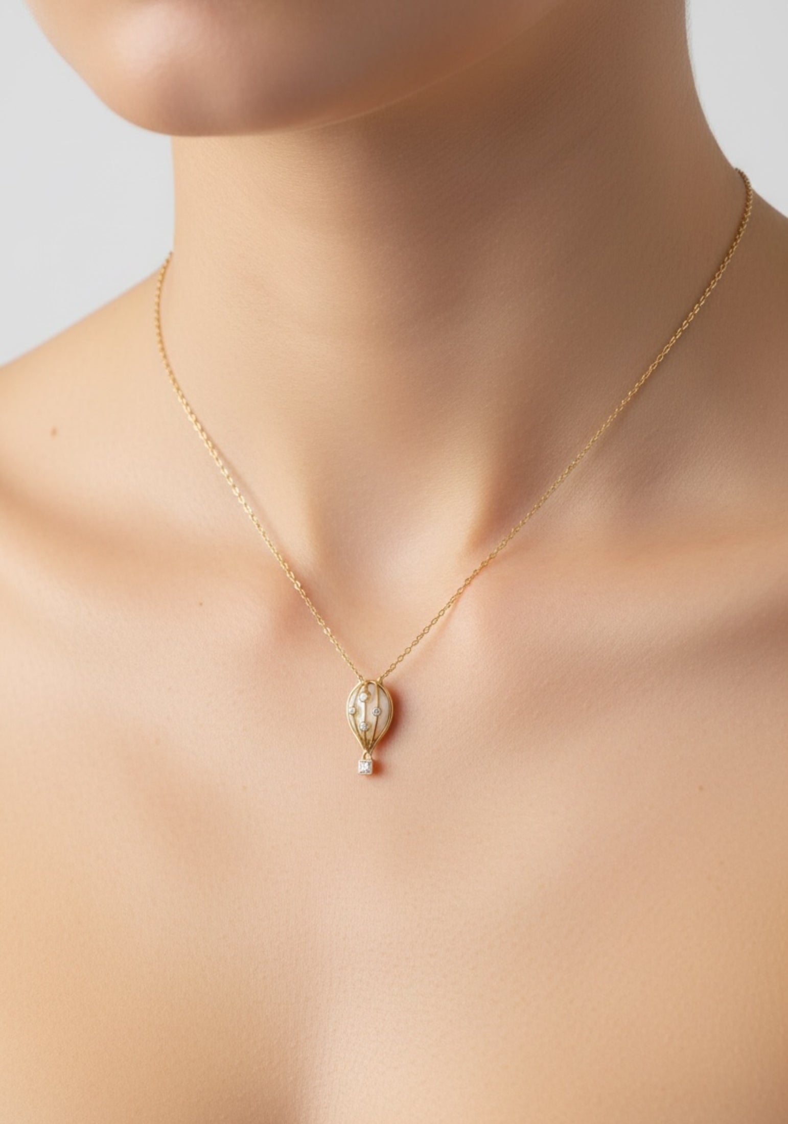 Gold necklace with a hot air balloon pendant on a woman