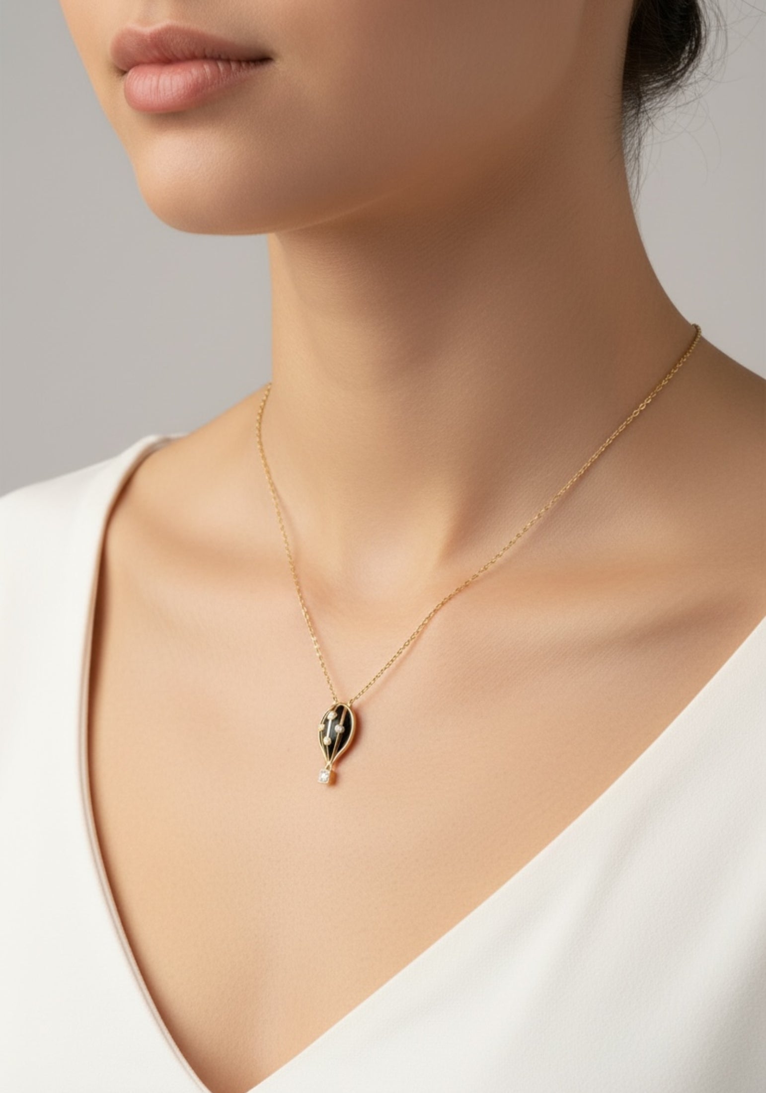 Necklace with a black hot air balloon pendant worn by a person against a neutral background