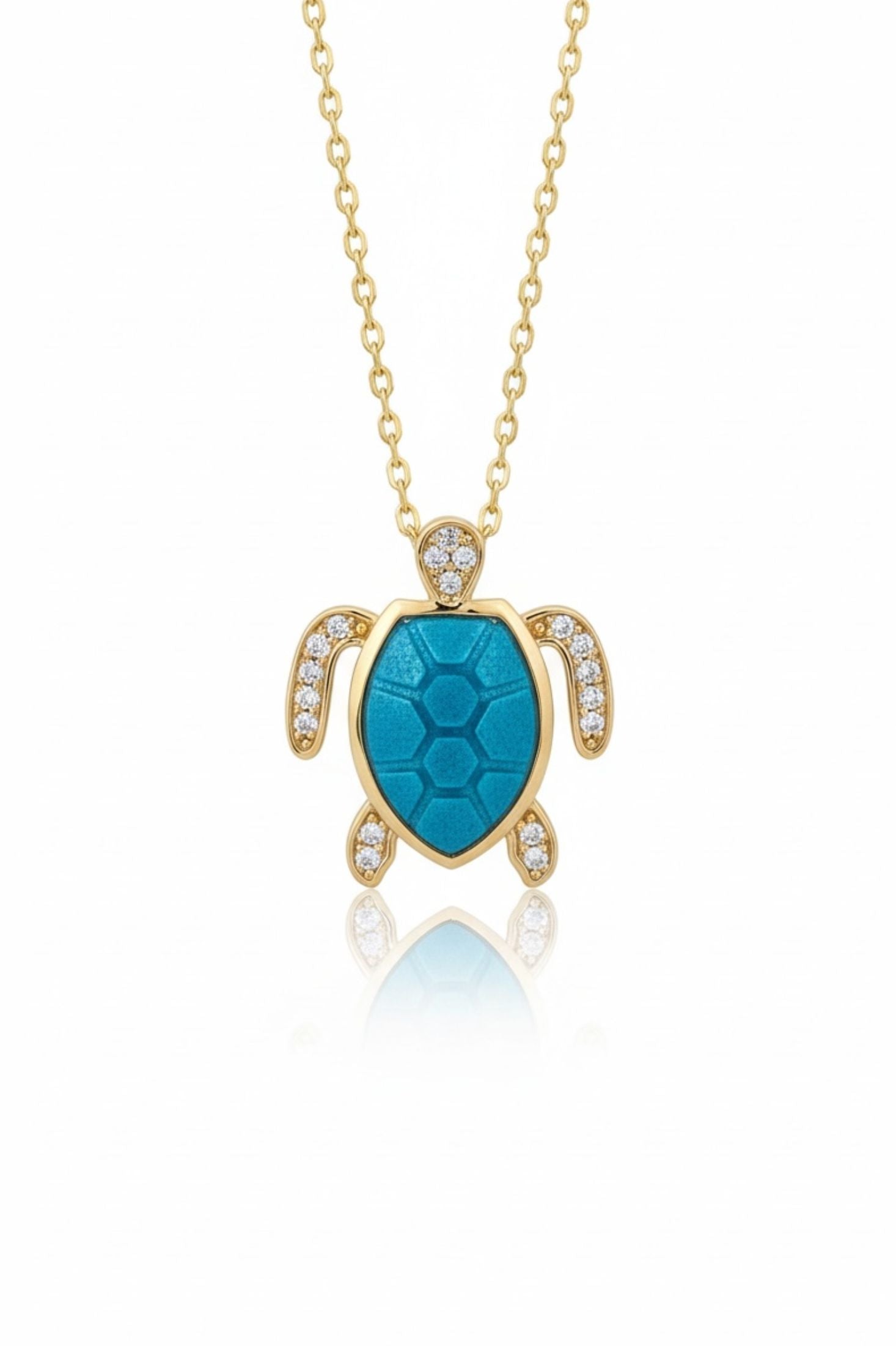 Gold turtle pendant with turquoise center and clear stones on a gold chain against a white background