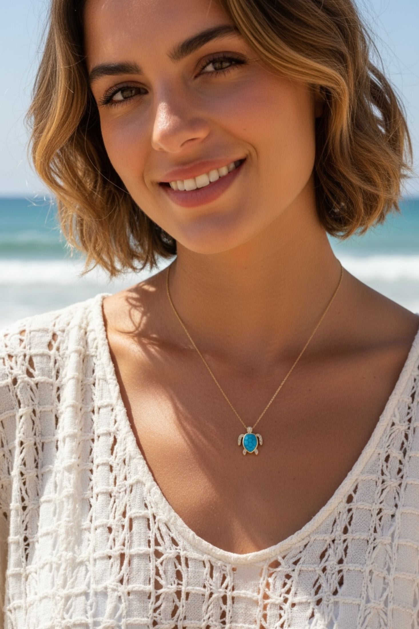 Woman wearing a turquoise turtle necklace with a blue pendant on a beach
