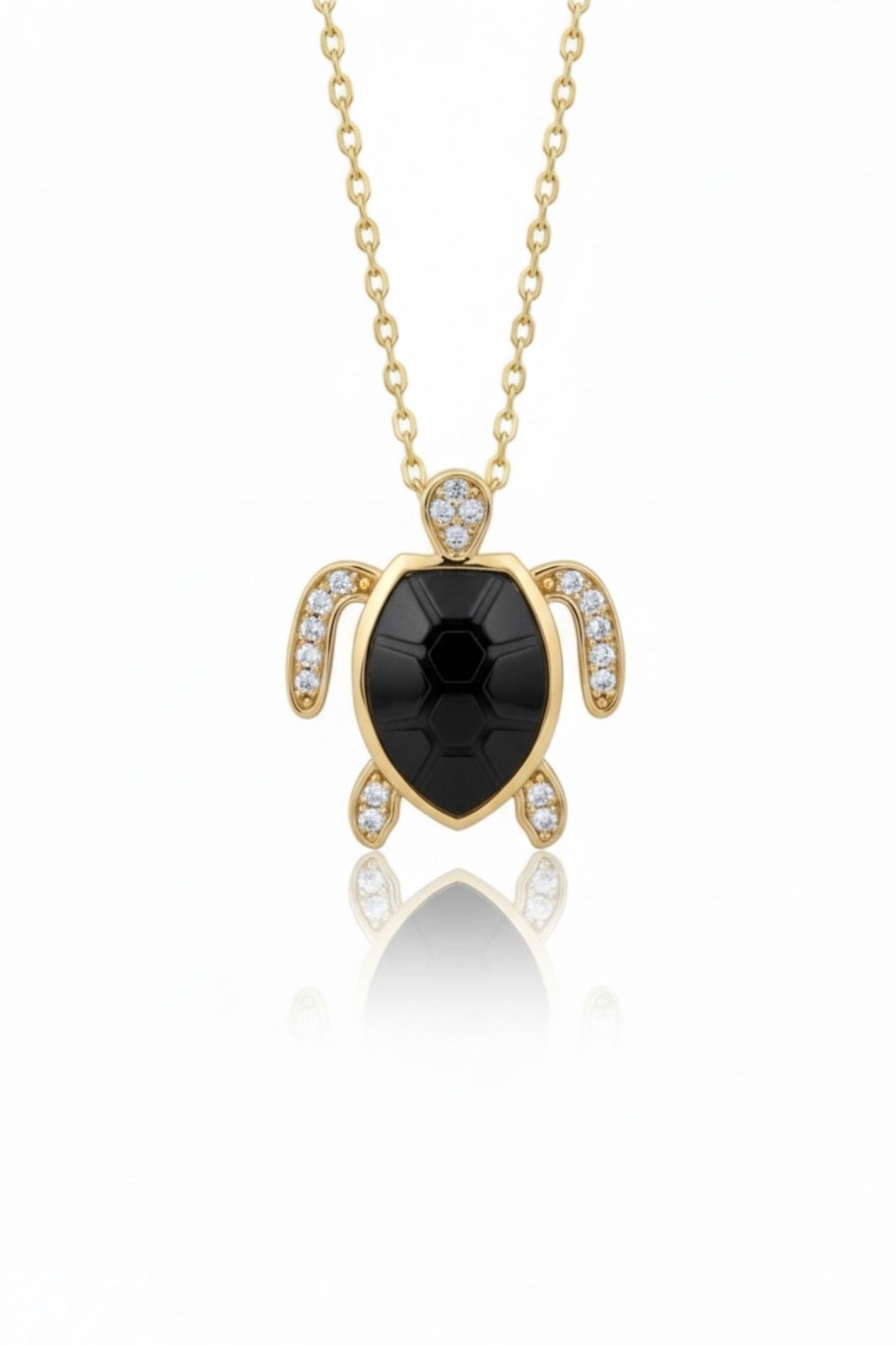 Gold turtle pendant necklace with black gemstone on a white background