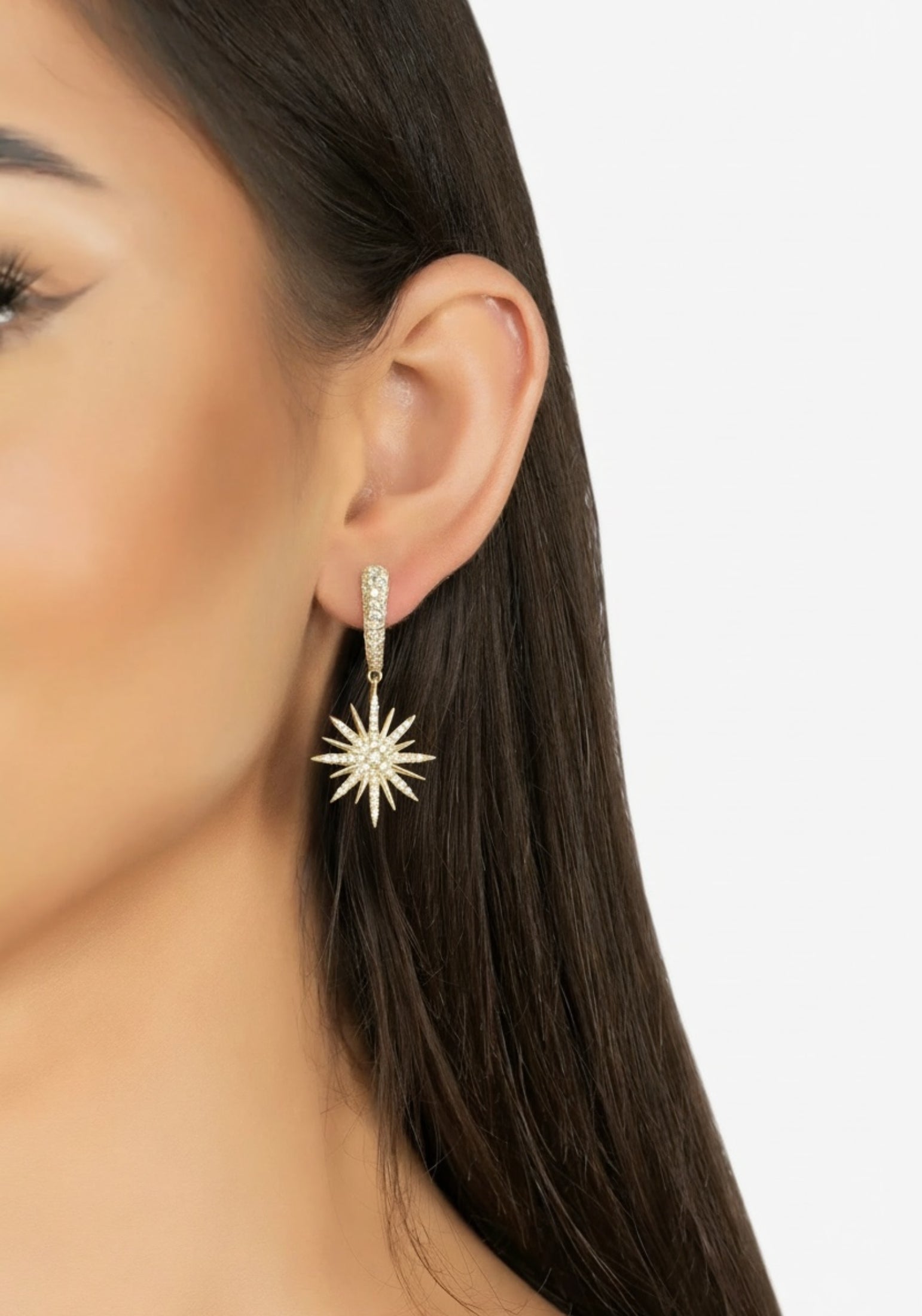 Close-up of a person wearing a star-shaped earring on a plain background