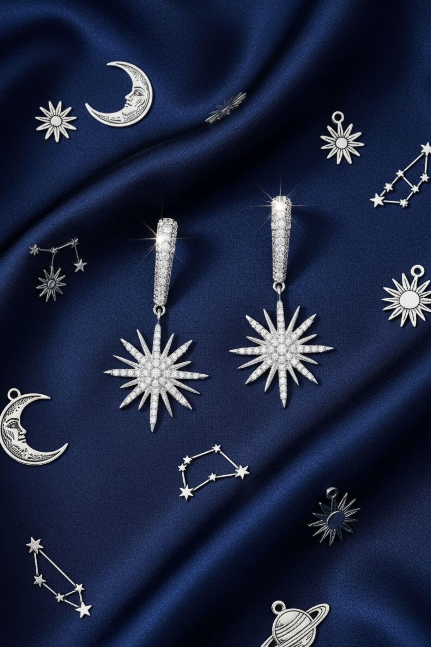 Silver star-shaped earrings with silver gemstones on a dark blue fabric background