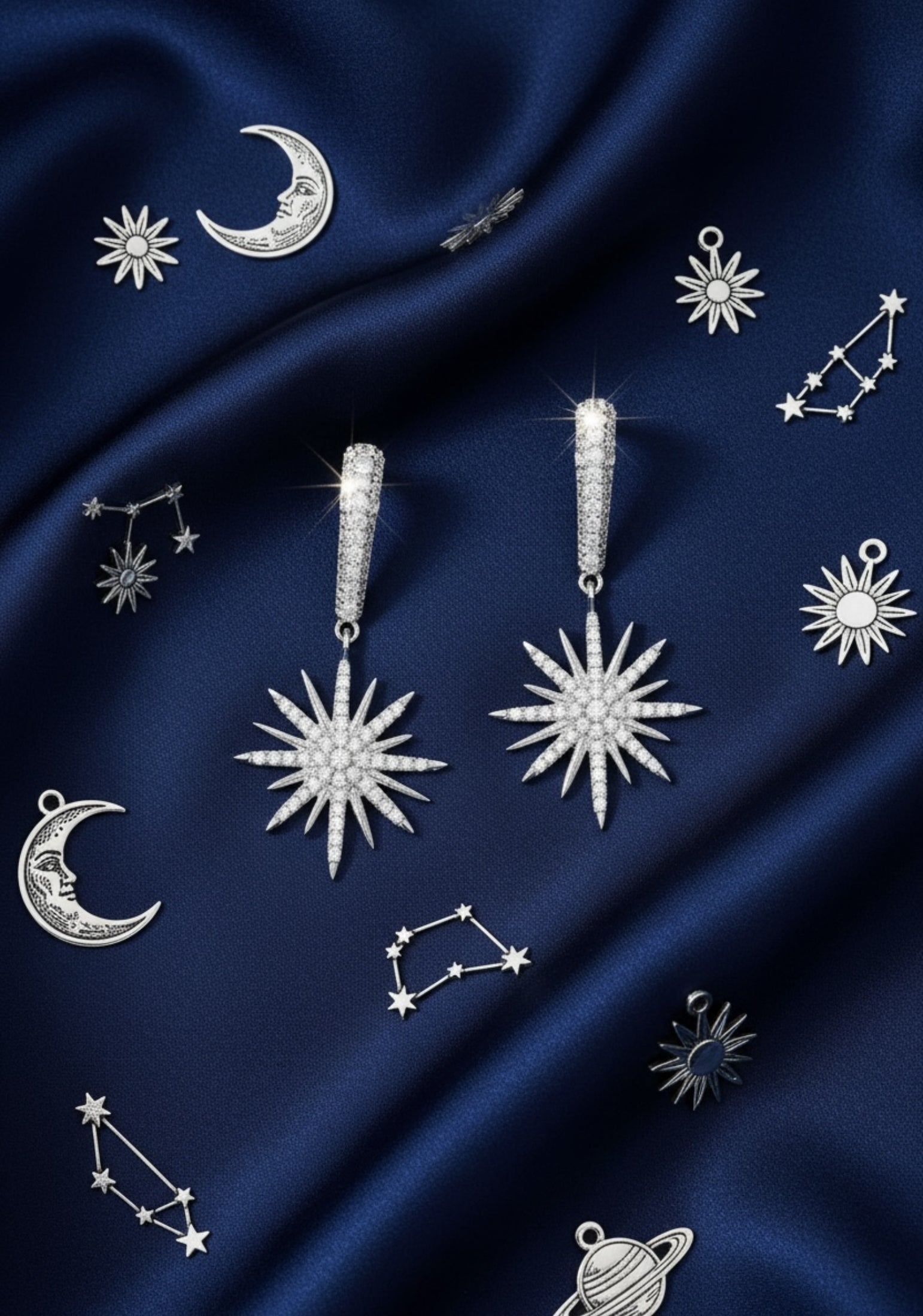 Silver star-shaped earrings with silver gemstones on a dark blue fabric background