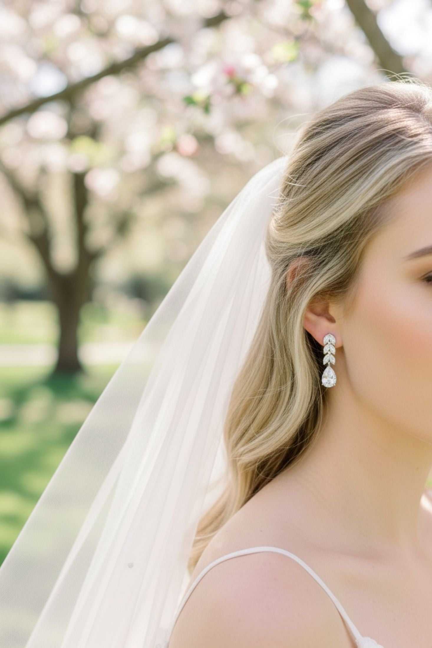 Bride with a veil and silver teardrop  earrings in a garden setting