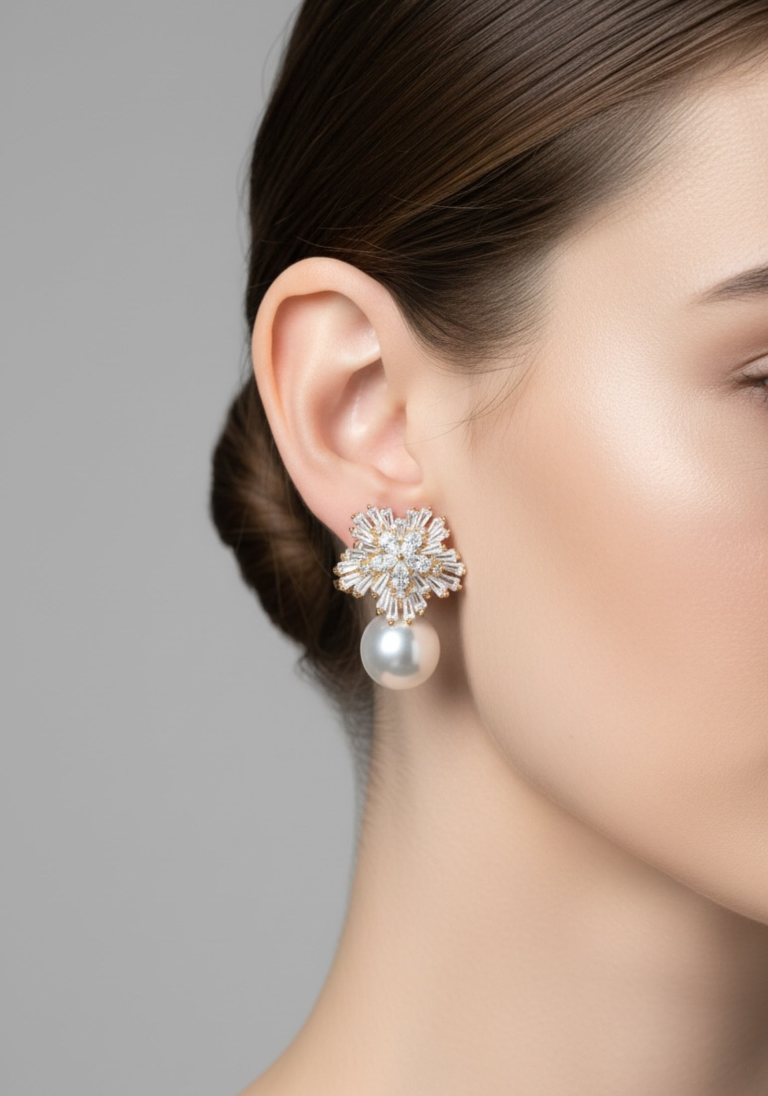 Close-up of a woman wearing a pearl earring with a gray background