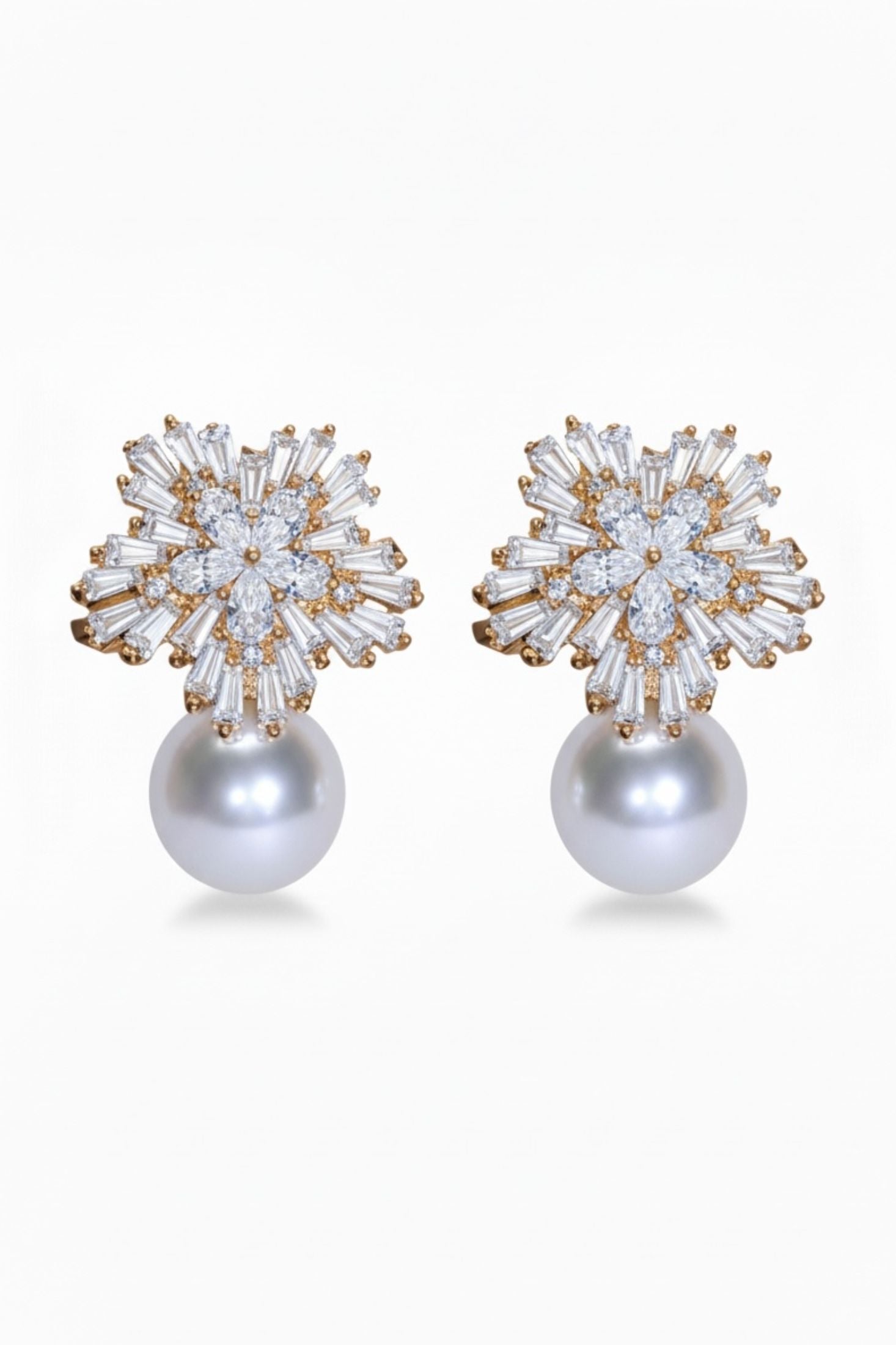 Pair of earrings with star-like top and pearl bottom on a white background
