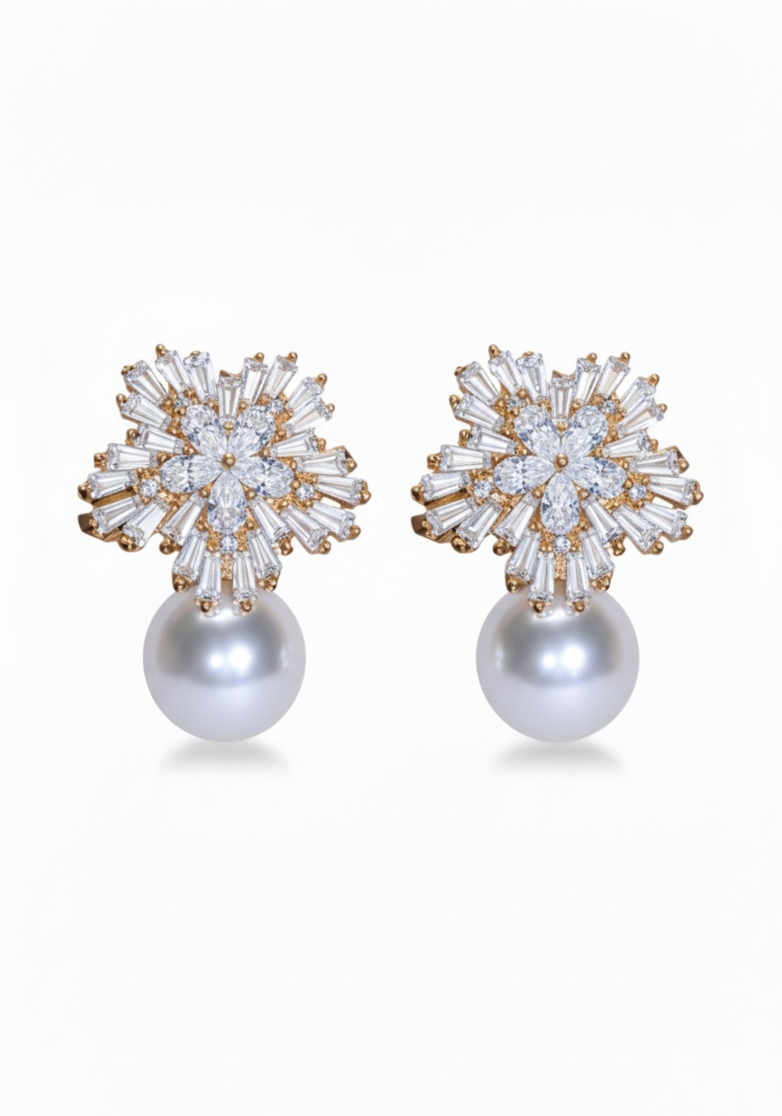 Pair of earrings with star-like top and pearl bottom on a white background